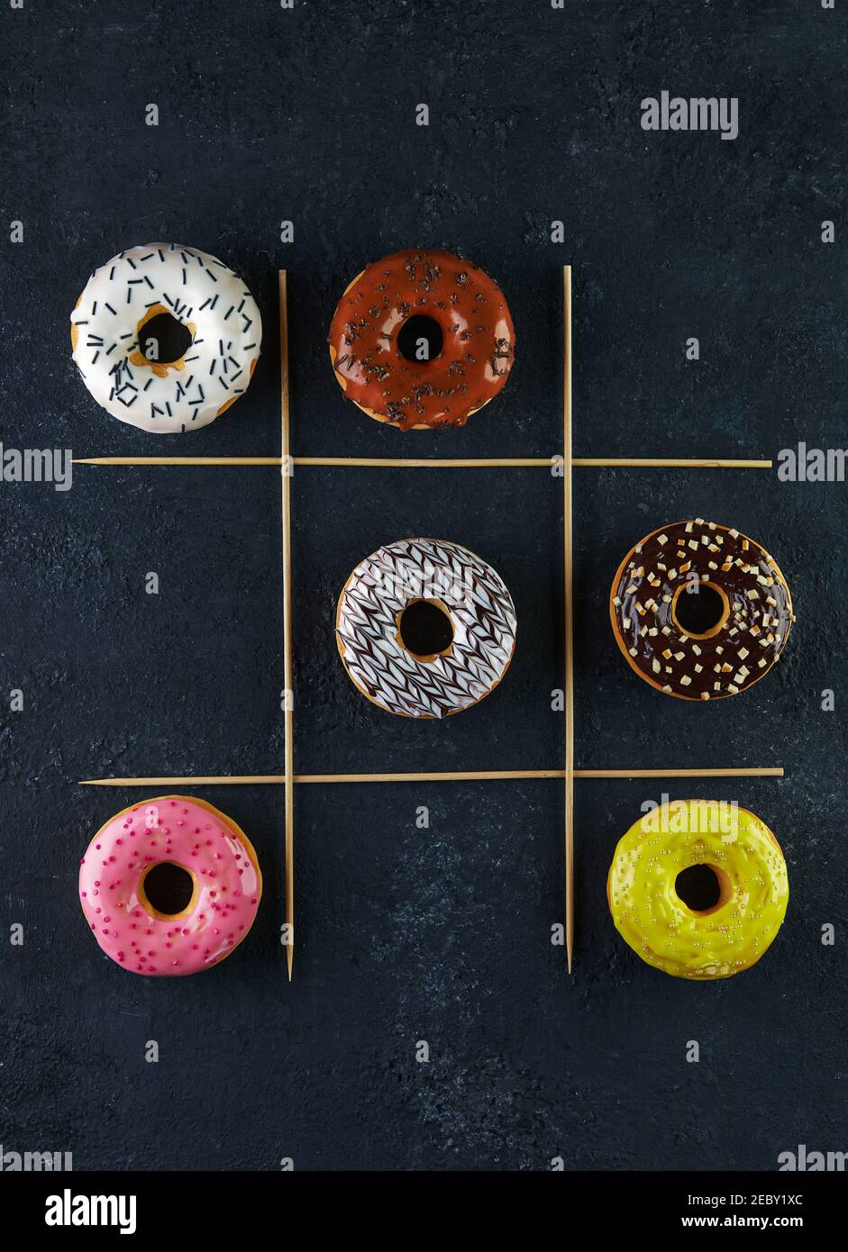 Multicolored donuts with glaze and sprinkles on a black background tic ...
