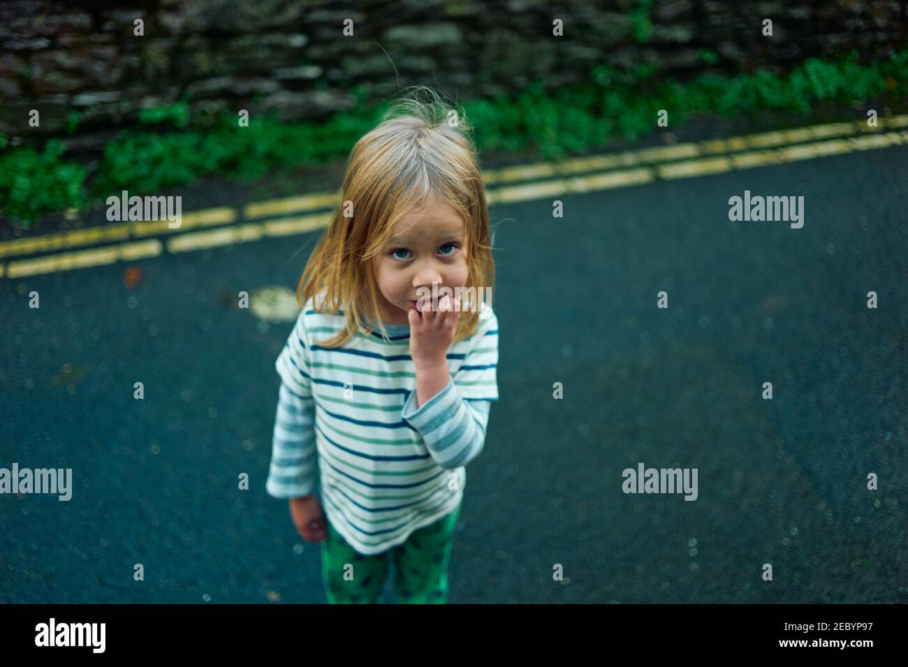 A little preschooler is standing in the road on a sunny autumn day Stock Photo