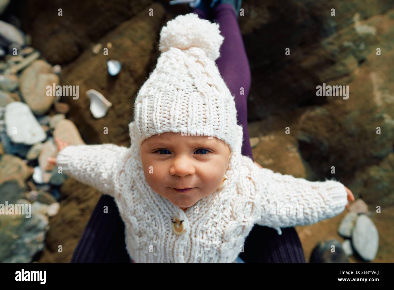 A little baby is resting on mothers lap on a beach in the winter Stock Photo