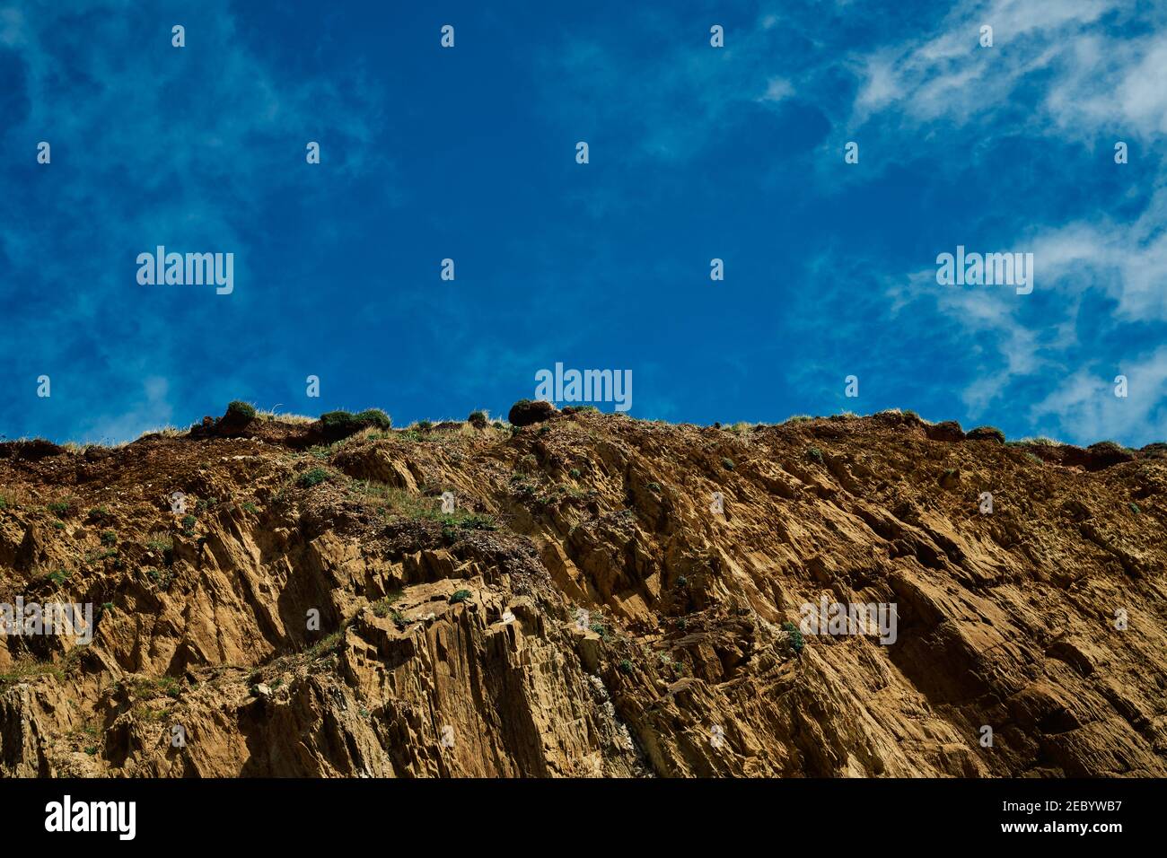 Rocks on a hillside against a bright blue sky Stock Photo