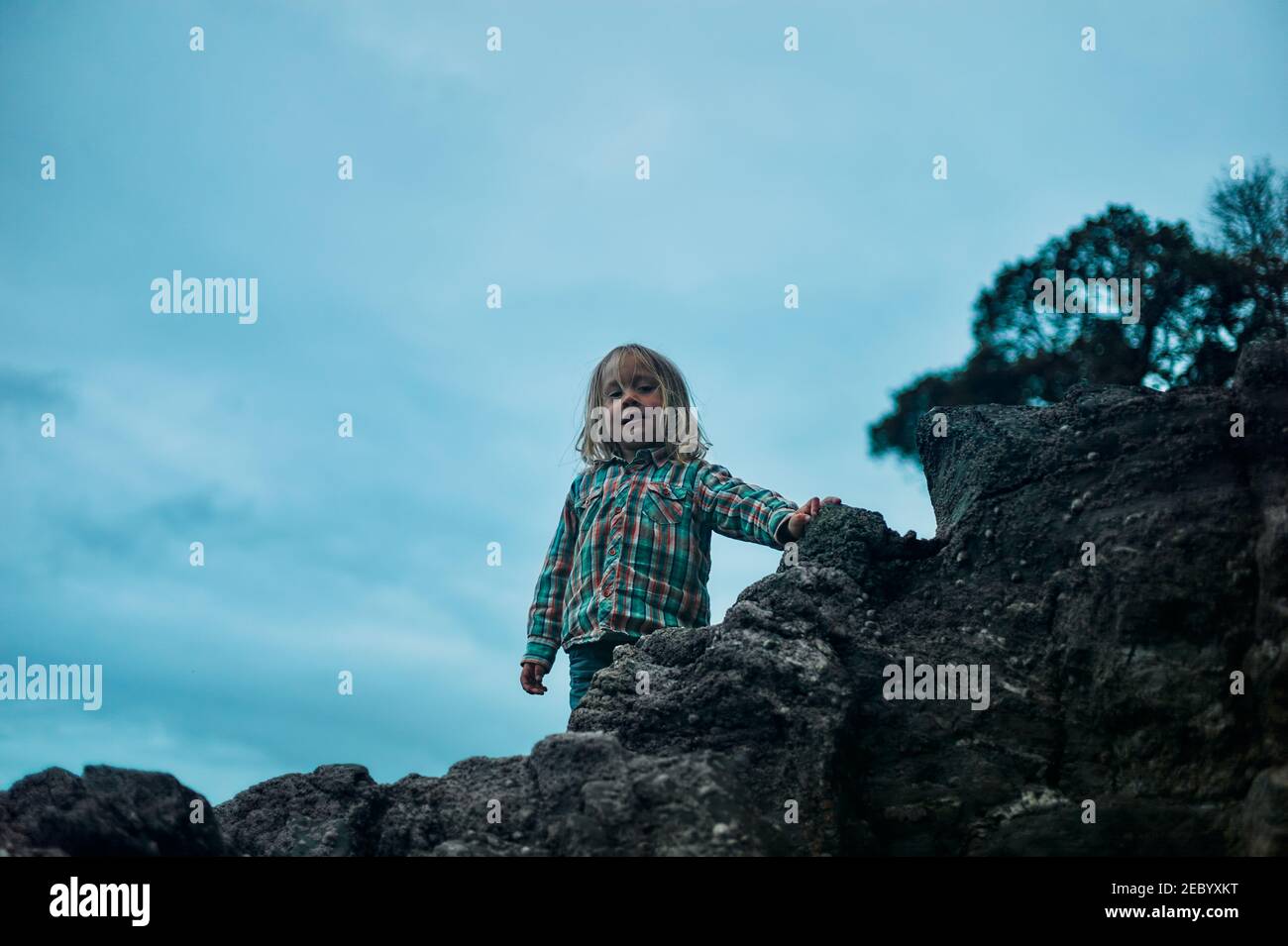A little preschooler is standing on a rock in the autumn Stock Photo