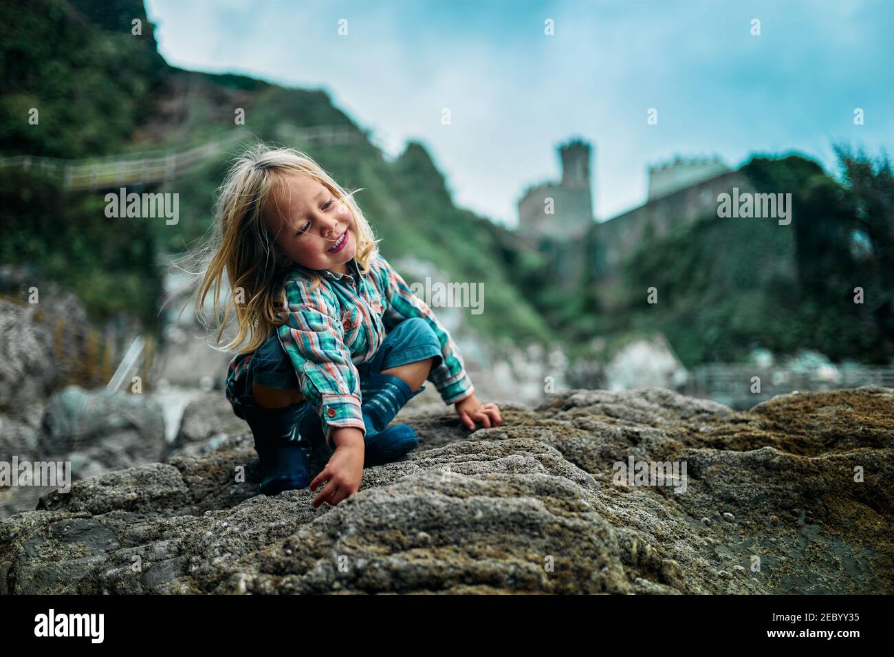 A little preschooler is climbing on some rocks in the autumn Stock Photo