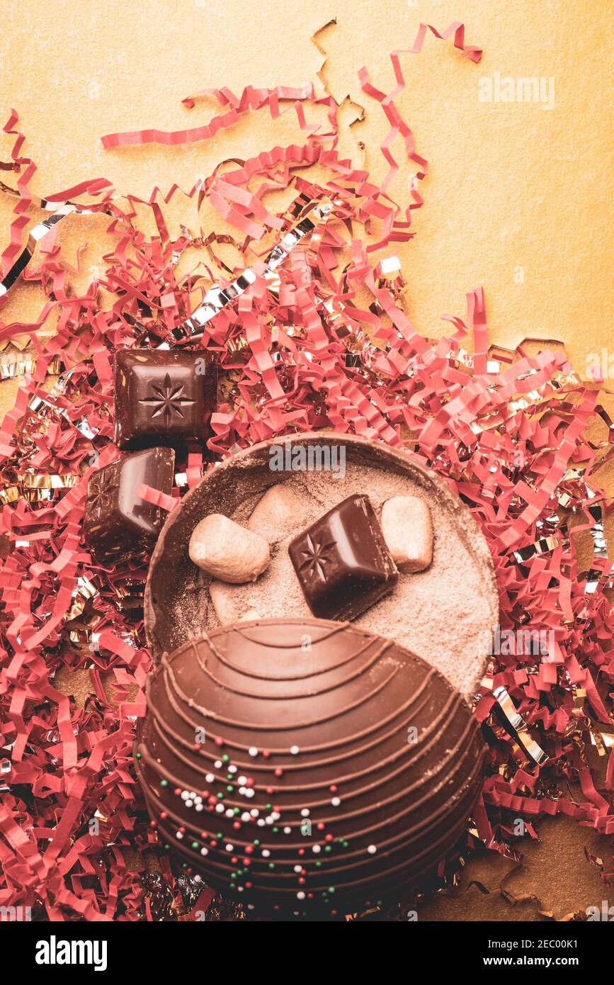 Flat lay of open cocoa bomb with confetti and gold background Stock Photo