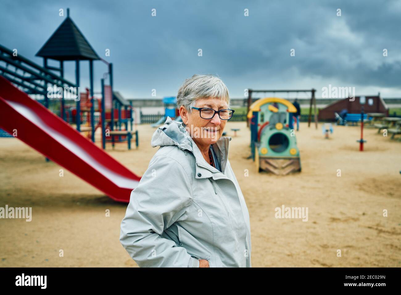 A senior woman is standing in a playground in the autumn Stock Photo