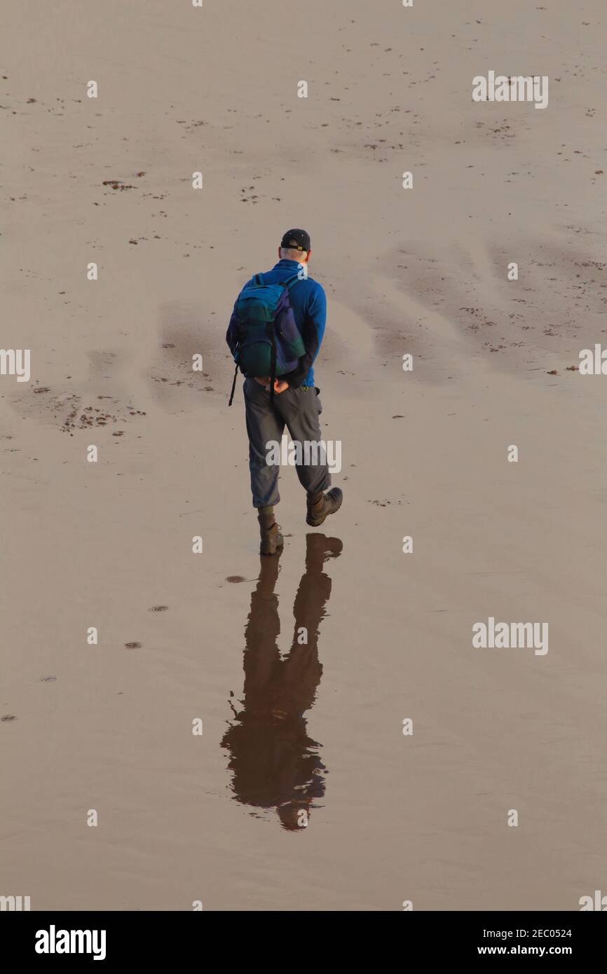 People walk on the sandy beach in town of Sidmouth, Devon. Reflection on the water surface. Stock Photo