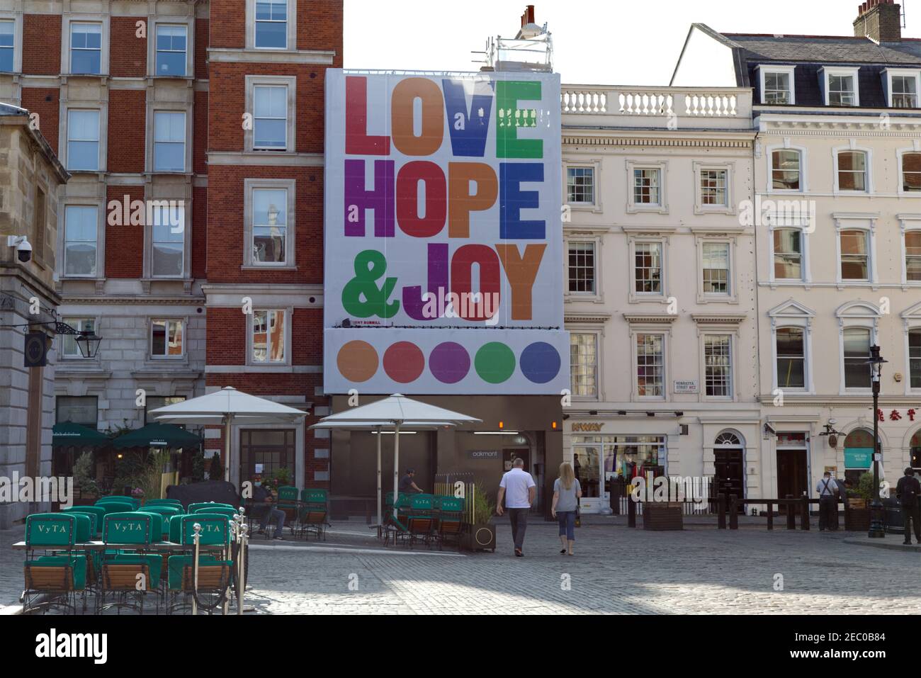 Covent Garden, with the words of Love, Hope & Joy emblazoned across a building overlooking the Piazza. Stock Photo