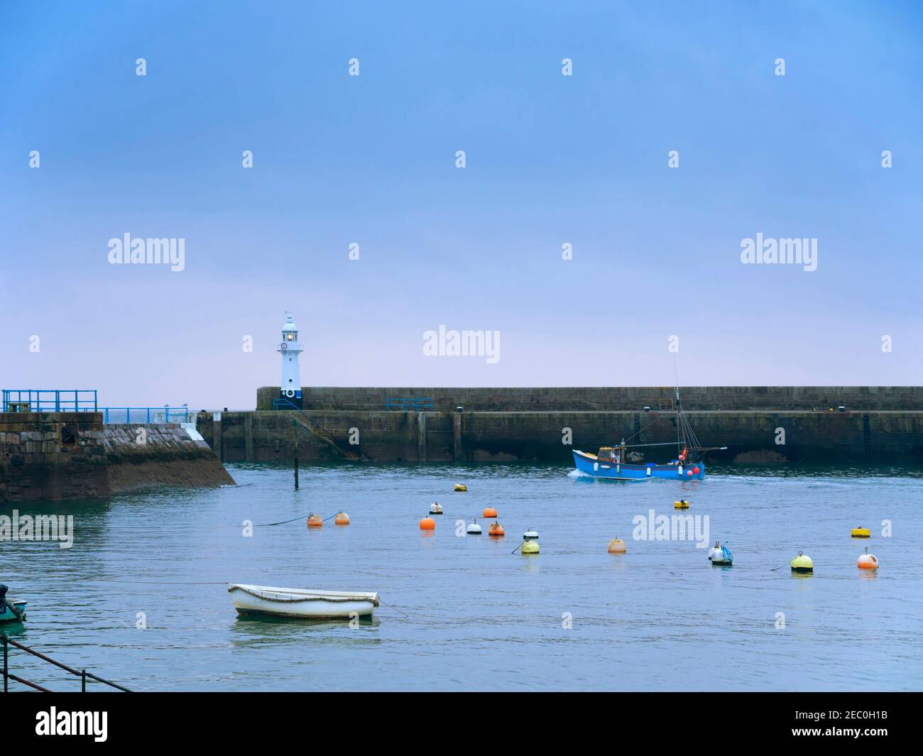 Mevagissey, Cornwall. A commercial fishing boat leaves the outer harbour at dusk. Stock Photo