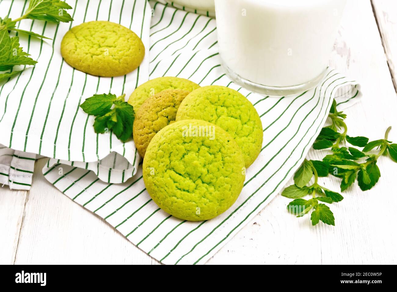 Green mint cookies on a towel with milk in a glass on wooden board background Stock Photo
