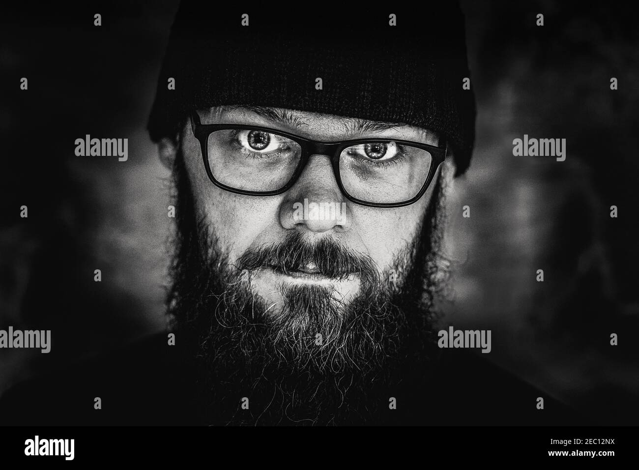 black and white portrait of a man with a beard and glasses, close-up, studio Stock Photo