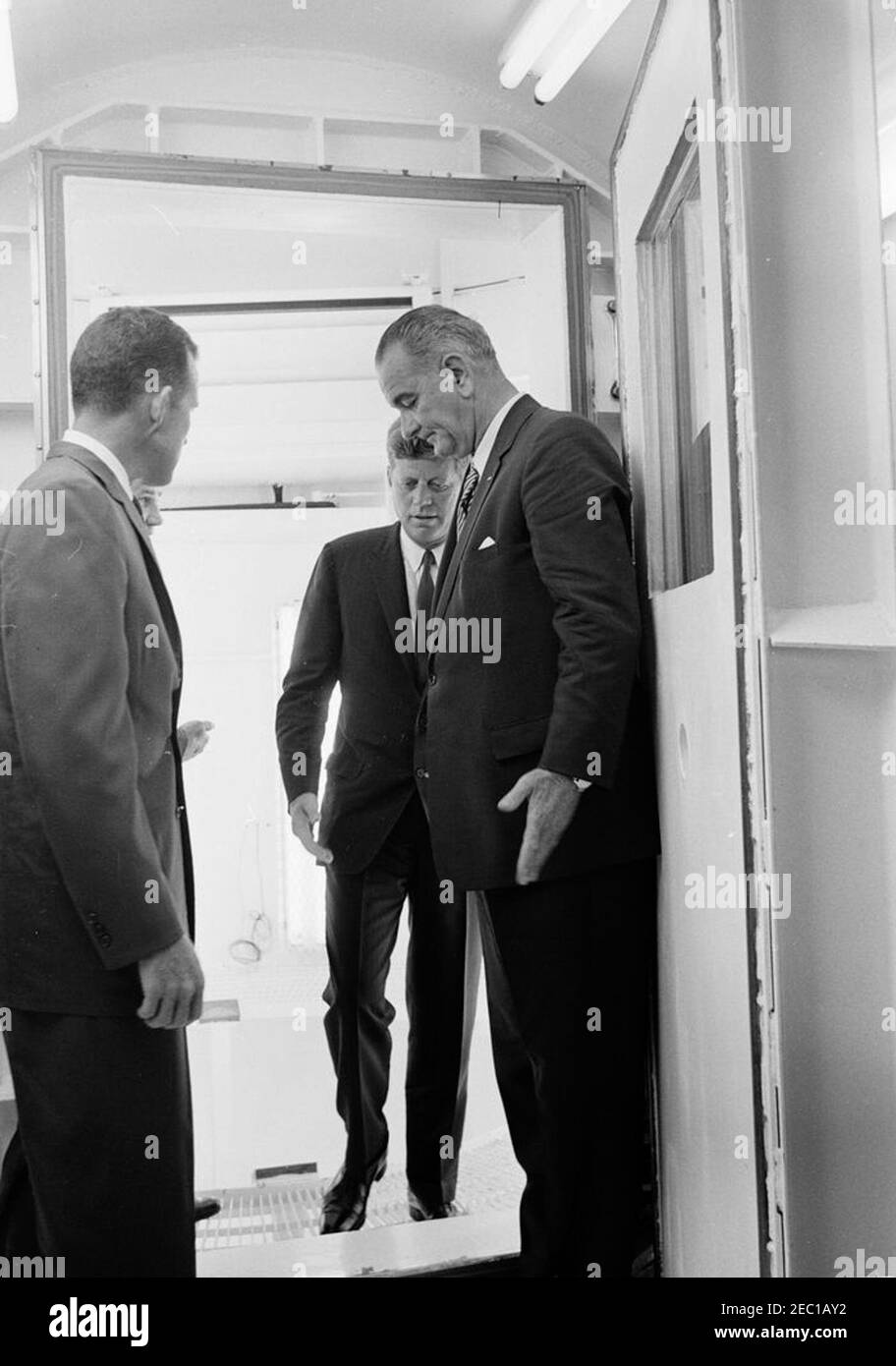 Inspection tour of NASA installations: Cape Canaveral Florida, 2:31PM. President John F. Kennedy (center) exits a high-altitude chamber, during a tour of Mercury spacecraft systems and equipment inside Hangar S at Cape Canaveral Air Force Station, Cape Canaveral, Florida. Astronaut Major L. Gordon Cooper (left, back to camera) and Vice President Lyndon B. Johnson stand in doorway. President Kennedy visited Cape Canaveral as part of a two-day inspection tour of National Aeronautics and Space Administration (NASA) field installations. Stock Photo