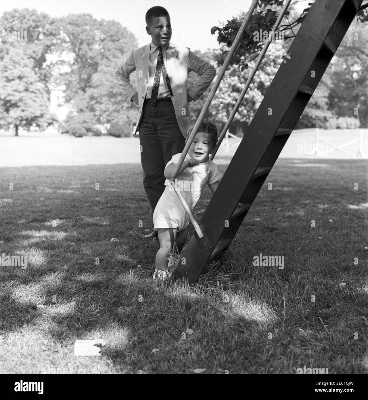Vice President Lyndon B. Johnson (LBJ) presents a new pony, u201cTexu201d to Caroline Kennedy (CBK); children playing on the South Lawn. John F. Kennedy, Jr., stands at the ladder of a tree house on the South Lawn of the White House; an unidentified boy stands behind him. Washington, D.C. Stock Photo