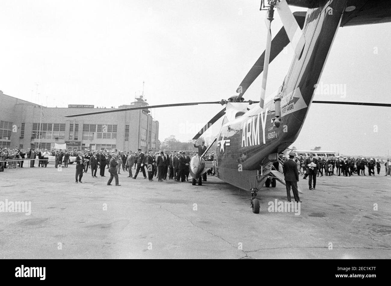 Congressional campaign trip: Detroit, Michigan, remarks at hotel, tour of city, departure. President John F. Kennedy (center) waves as he boards a United States Army helicopter prior to his departure from Detroit City Airport for Flint, Michigan, during a congressional campaign trip. Detroit, Michigan. Stock Photo