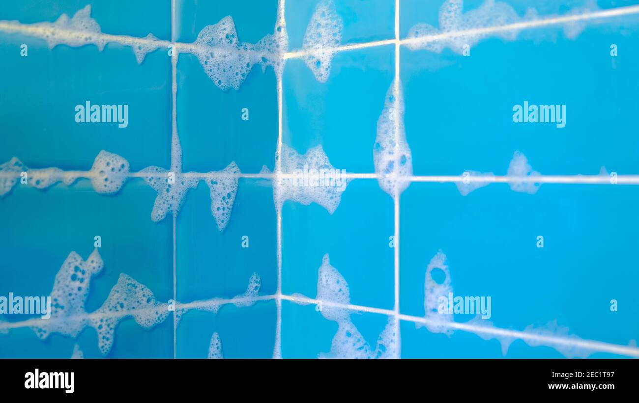 Bathroom shower blue tiles with lather suds soap foam after shower closeup selective focus background Stock Photo