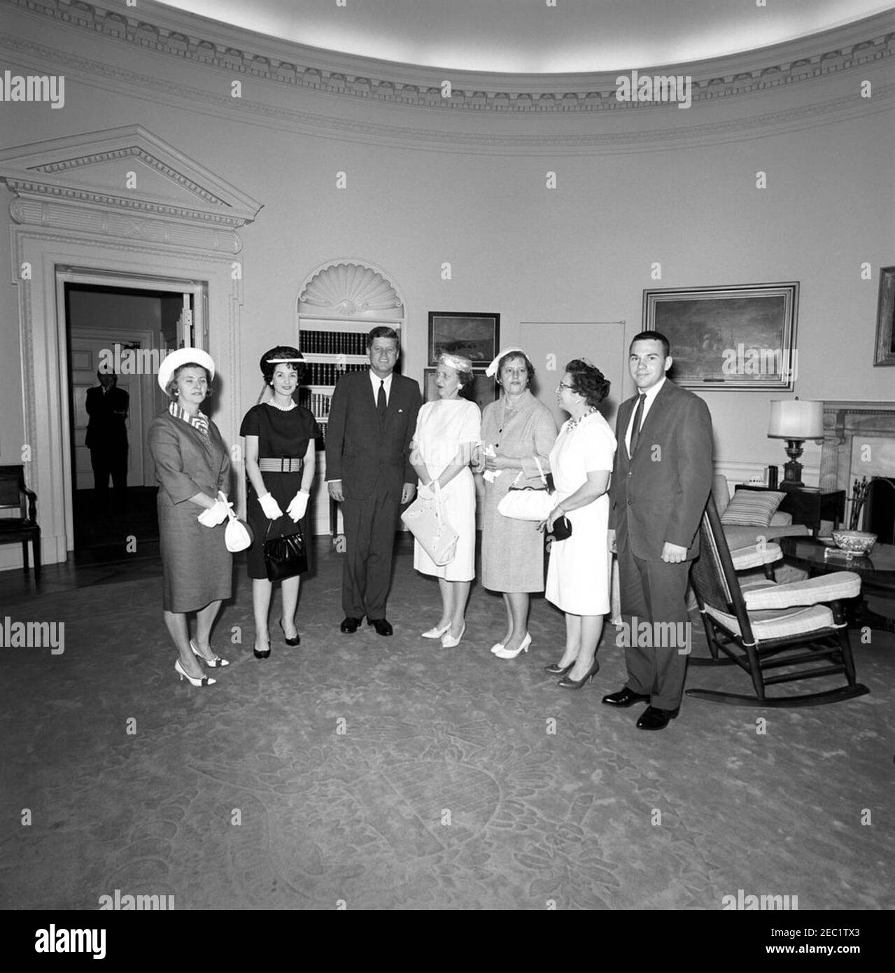 Visit of wives of Ohio newspaper publishers, 12:30PM. President John F. Kennedy visits with wives of newspaper publishers from Ohio. Those present include: Helen Dix, Evelyn M. Cook, Lucile A. Troyer, Josephine Sicuro, and Ruth Fairchild. Special Assistant to the President, Kenneth P. Ou2019Donnell, stands in background (through doorway). Oval Office, White House, Washington, D.C. Stock Photo