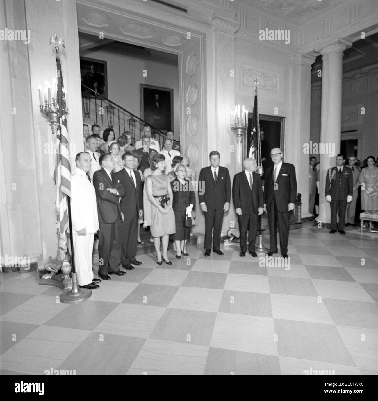 Military Reception at the White House, 6:00PM. President John F. Kennedy, First Lady Jacqueline Kennedy, and others attend a military reception at the White House. Also pictured (standing at grand staircase): Chairman of the Joint Chiefs of Staff, General Lyman L. Lemnitzer, and his wife, Katherine Lemnitzer; Secretary of the Army, Elvis J. Stahr, Jr., and his wife, Dorothy Stahr; Secretary of Defense, Robert S. McNamara; Secretary of the Air Force, Eugene M. Zuckert, and his wife, Barbara Jackman Zuckert; Secretary of the Navy, Fred Korth, and his wife, Vera Korth; General Maxwell D. Taylor a Stock Photo