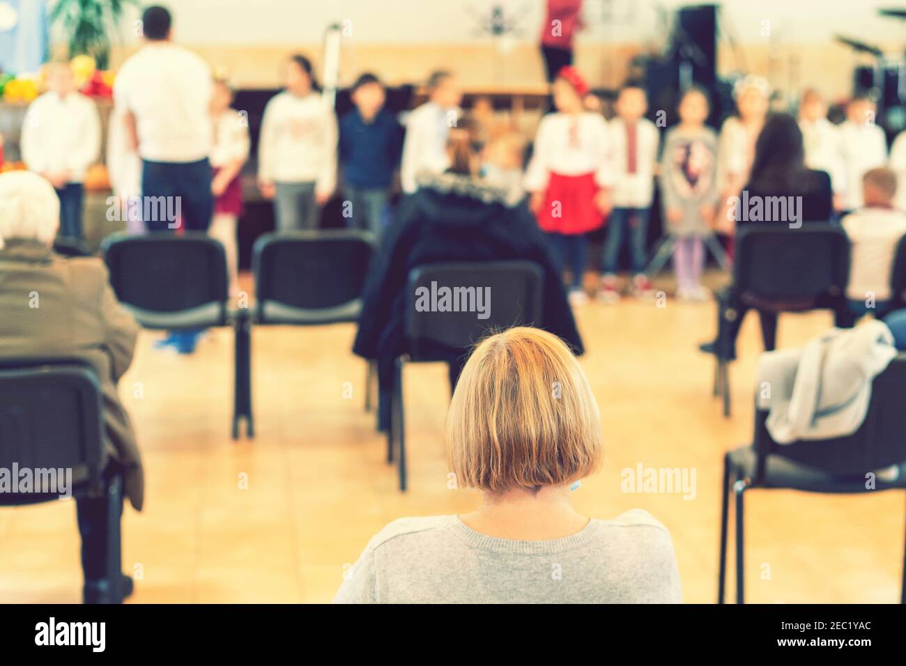 Parents at the performance of children in kindergarten or school. Children on stage. Many parents are watching the kids performance in the hall during Stock Photo