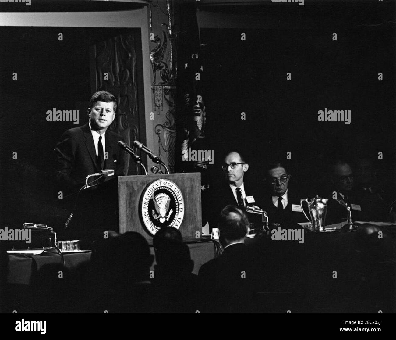Address to the Symposium on Economic Growth, 9:53AM. President John F. Kennedy (at lectern) delivers remarks at the American Bankers Association (ABA) Symposium on Economic Growth. Seated right of lectern: Chairman of the First National Bank in Thomson, Georgia, M. Monroe Kimbrel; Managing Director of the International Monetary Fund (IMF), Per Jacobsson. Mayflower Hotel, Washington, D.C. Stock Photo