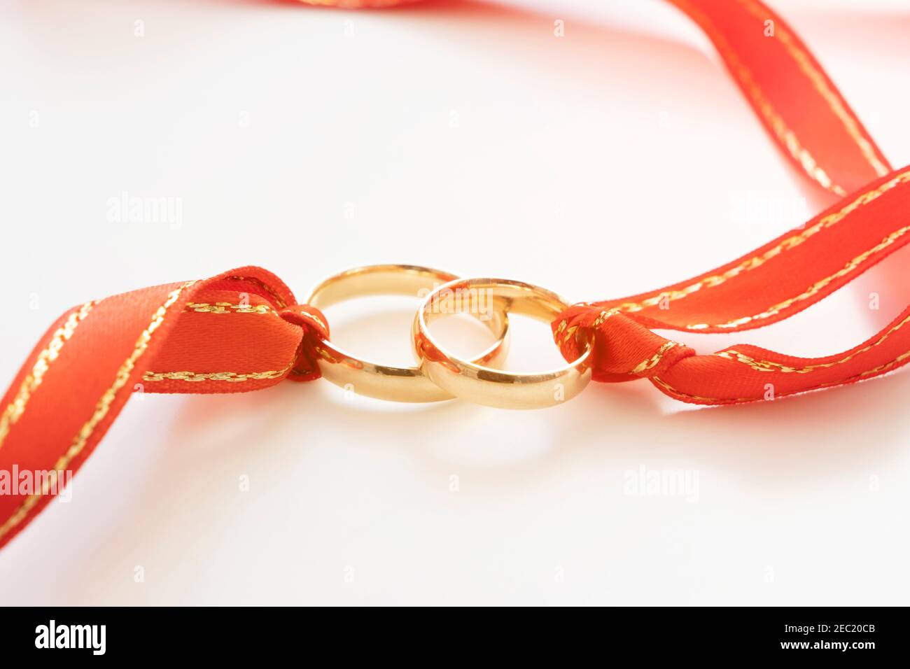 wedding rings and red ribbon on white background Stock Photo - Alamy