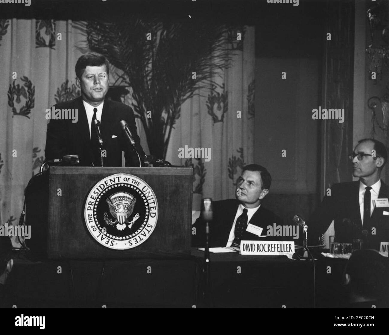 Address to the Symposium on Economic Growth, 9:53AM. President John F. Kennedy (at lectern) delivers remarks at the American Bankers Association (ABA) Symposium on Economic Growth. Seated right of lectern: President of Chase Manhattan Bank, David Rockefeller; Chairman of the First National Bank in Thomson, Georgia, M. Monroe Kimbrel. Mayflower Hotel, Washington, D.C. Stock Photo