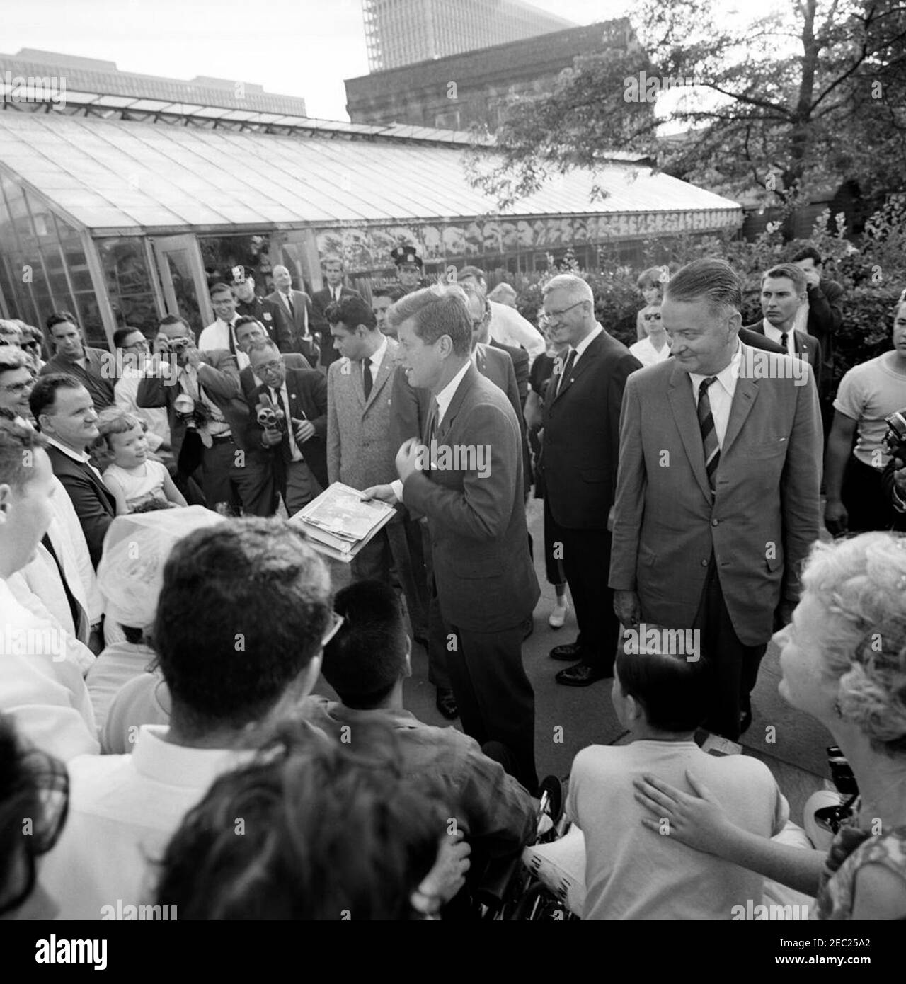 Trip to New York and Connecticut: New York City, President John F. Kennedy Visits with Patients at the Institute of Physical Medicine and Rehabilitation, New York University Medical Center, 5:45PM. President John F. Kennedy greets patients after visiting his father, Ambassador Joseph P. Kennedy, Sr., at the Institute of Physical Medicine and Rehabilitation at New York University Medical Center. Founder and Director of the Institute, Dr. Howard A. Rusk, stands right of President Kennedy; White House Secret Service agent, Toby Chandler, stands at right in background. New York City, New York. [Ph Stock Photo