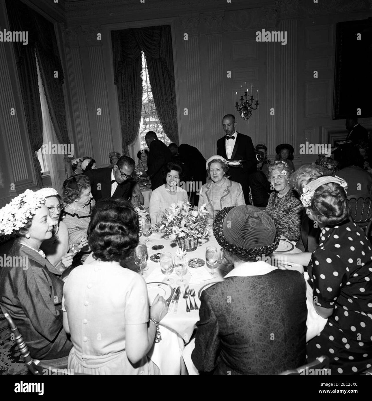 First Lady Jacqueline Kennedyu0027s (JBK) luncheon for Senatorsu0027 wives. Lady Bird Johnson (center) attends a luncheon for senatorsu2019 wives, given by First Lady Jacqueline Kennedy in the State Dining Room of the White House, Washington, D.C. Also seated at table in foreground: Henrietta Hill (wife of Senator Lister Hill of Alabama); Frances Marion Grant Bennett, wife of Senator Wallace Bennett of Utah. Grace Murphy Dodd (wife of Senator Thomas Dodd of Connecticut) sits at right in background. Stock Photo