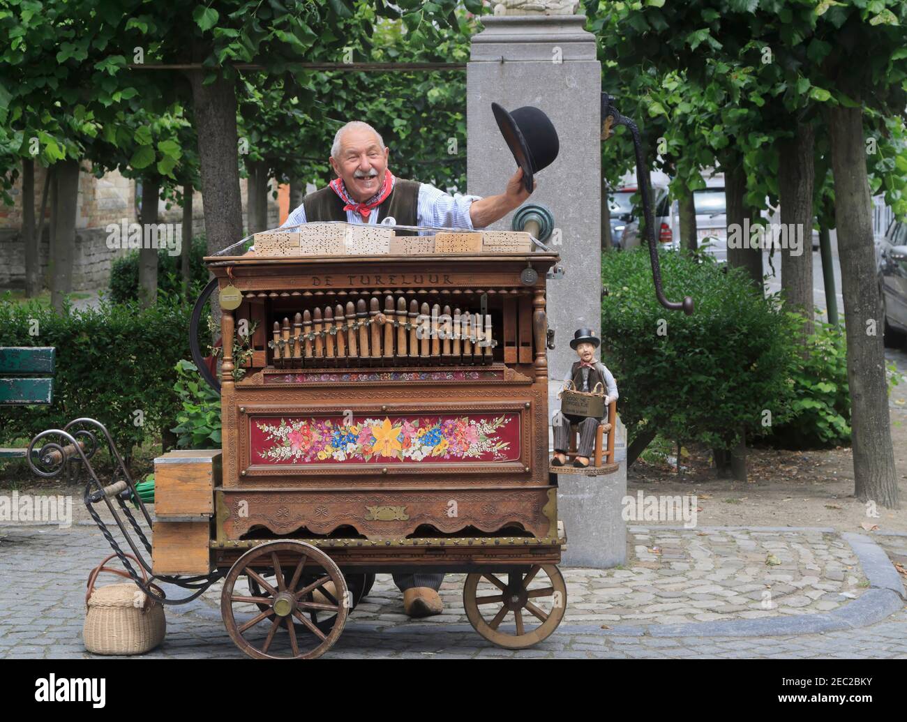 Street entertainer in Bruges, Belgium. Elderly gentleman performs for tourists with an old fashioned barrel organ. Stock Photo