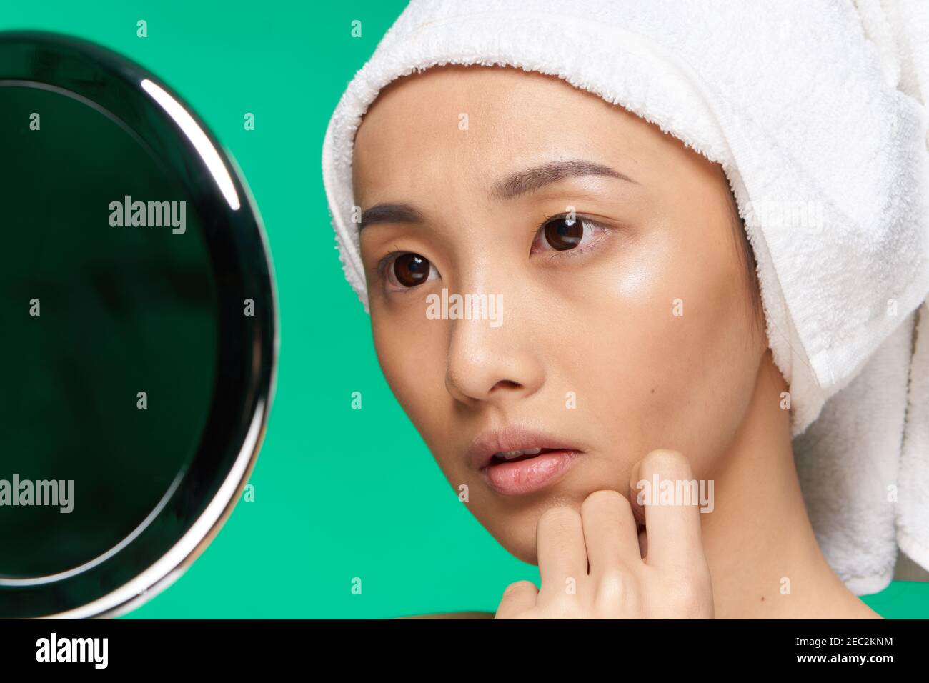 pretty asian woman looking in the mirror and touching her face close-up ...
