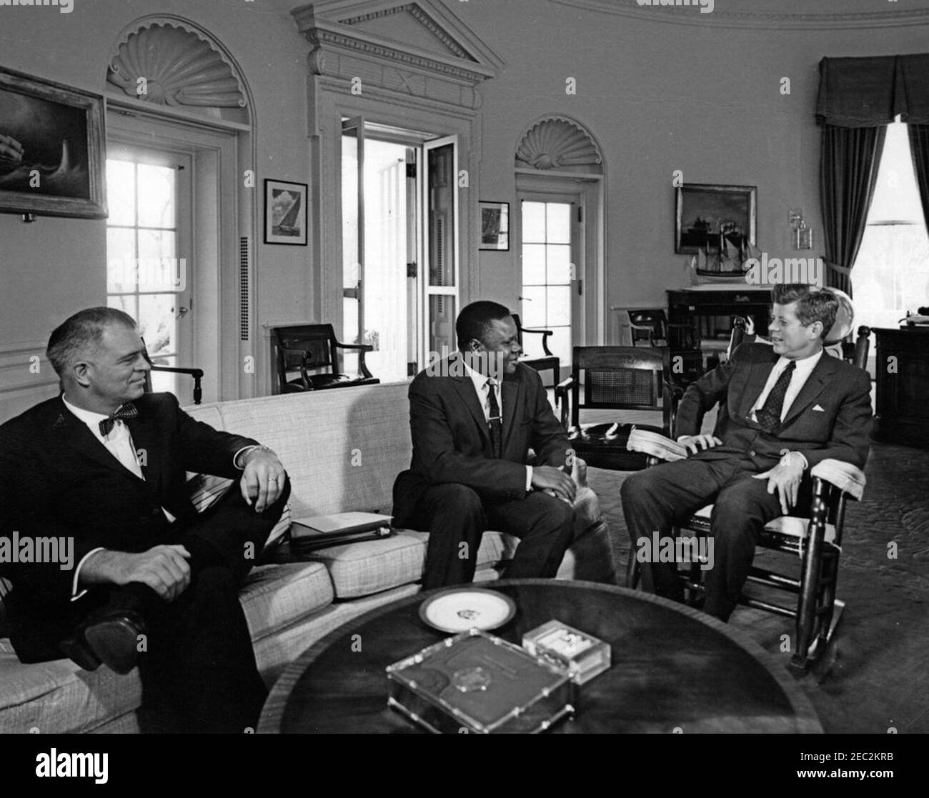 Meeting with the Ambassador of Guinea, Karim Bangoura, 10:00AM. President John F. Kennedy (in rocking chair) meets with Ambassador of the Republic of Guinea, Karim Bangoura, in the Oval Office of the White House, Washington, D.C. Assistant Secretary of State for African Affairs, G. Mennen u0022Soapyu0022 Williams, sits at far left. Stock Photo