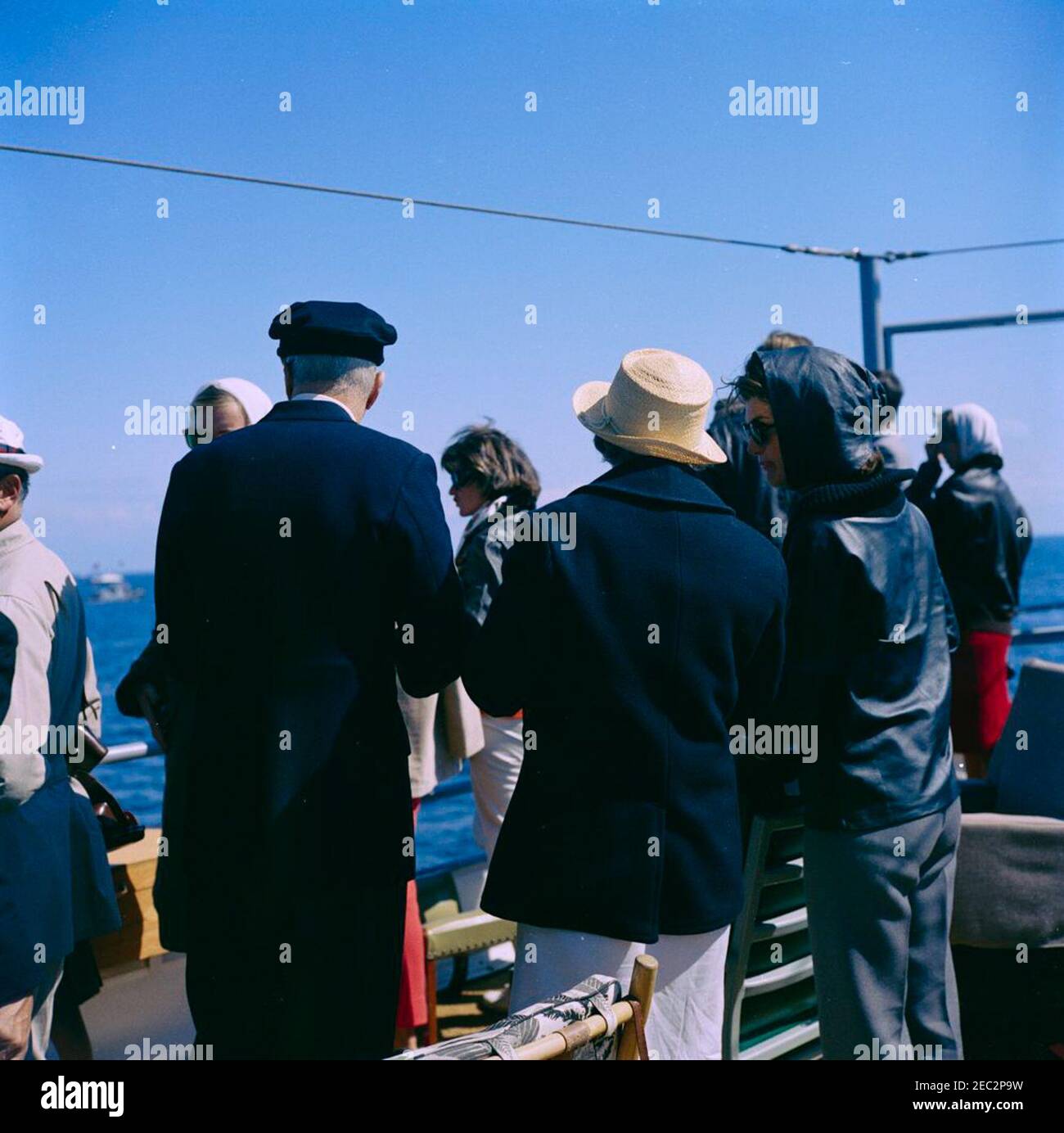 President Kennedy watches the 4th Americau0027s Cup Race. First Lady Jacqueline Kennedy (right) visits with Gertrude Conaway Vanderbilt and Harold S. Vanderbilt aboard the USS Joseph P. Kennedy, Jr., during the fourth race of the 1962 Americau0027s Cup. Jean Kennedy Smith stands at center in background. Newport, Rhode Island. Stock Photo