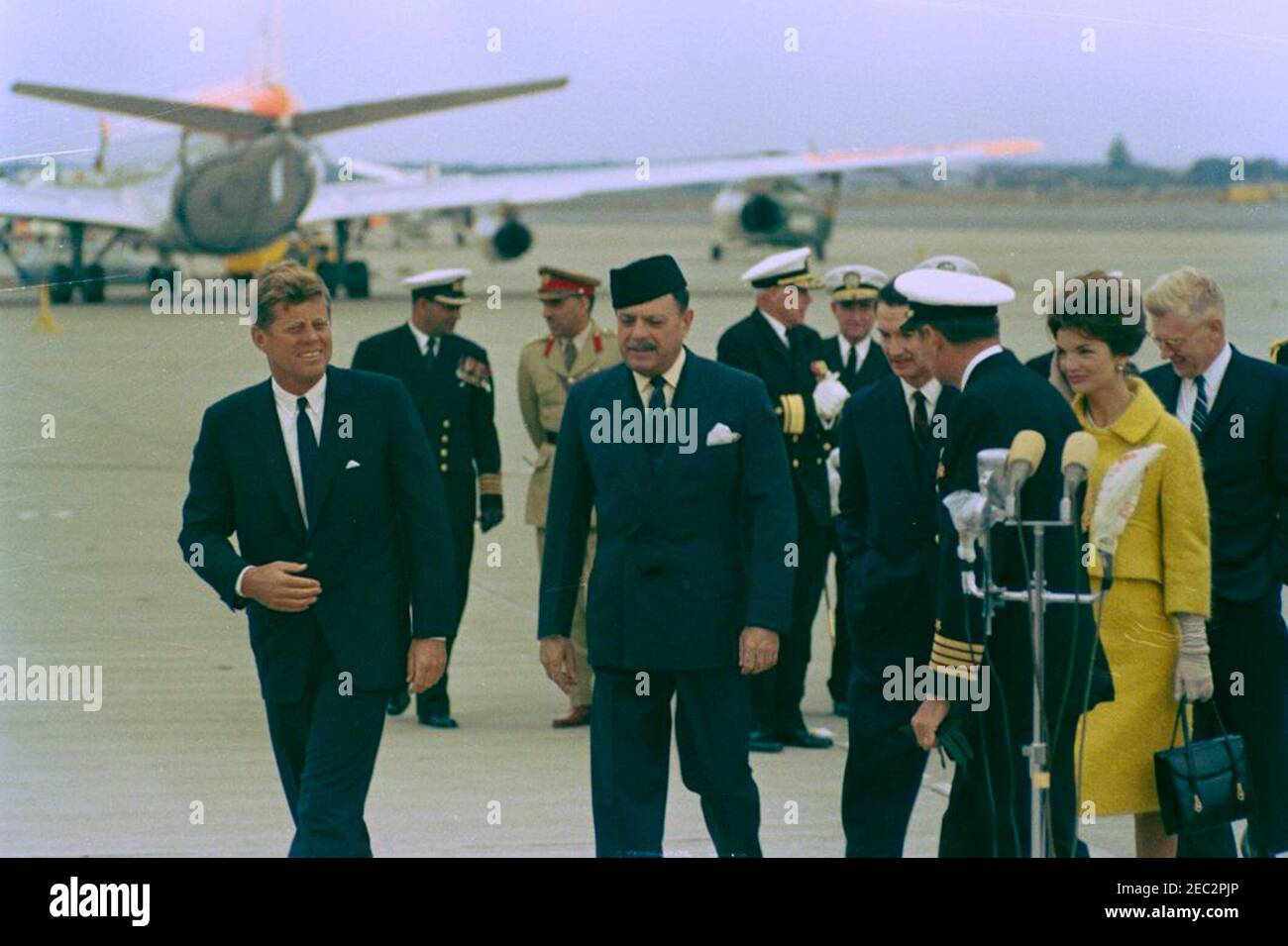 Visit of Muhammad Ayub Khan, President of Pakistan, Newport, Rhode Island. President John F. Kennedy and First Lady Jacqueline Kennedy walk with President of Pakistan, Muhammad Ayub Khan, following his arrival at Quonset Point Naval Air Station. Left to right (in foreground): President Kennedy; President Ayub Khan; U.S. Ambassador to Pakistan, Walter P. McConaughy; Naval Aide to President Kennedy, Captain Tazewell T. Shepard, Jr. (facing away); Mrs. Kennedy; U.S. Assistant Secretary of State for Near Eastern and South Asian Affairs, Phillips Talbot. North Kingstown, Rhode Island. [Scratches on Stock Photo