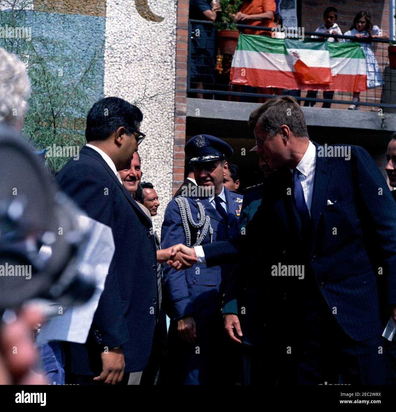 Trip to Mexico: Tour and address at the Independencia Housing Project, 9:35AM. President John F. Kennedy visits with crowds during a tour of the Unidad Independencia (Independencia Housing Project) in Mexico City, Mexico. Standing with President Kennedy: Air Force Aide to President Kennedy, Brigadier General Godfrey T. McHugh; General Cristu00f3bal Guzmu00e1n Cu00e1rdenas; U.S. State Department interpreter, Donald Barnes. Stock Photo