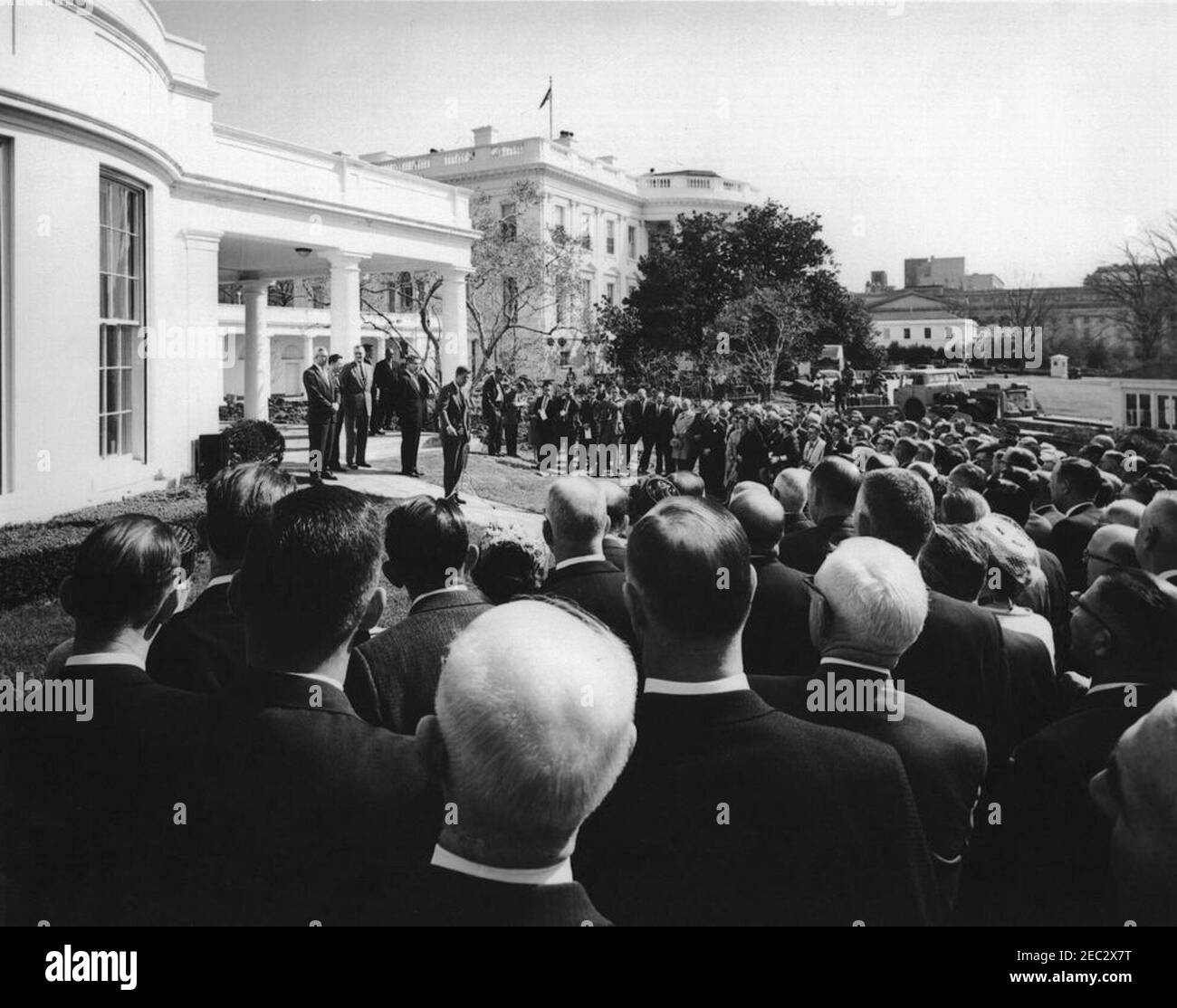 Meeting with members of the Agricultural Stabilization u0026 Conservation Committees, 9:45AM. President John F. Kennedy (back left) addresses members of the Agricultural Stabilization and Conservation (ASC) committees on the West Wing Lawn of the White House, Washington, D.C. Standing behind President Kennedy are (L-R): Assistant Secretary of Agriculture for Marketing and Foreign Agriculture John P. Duncan, Jr., two unidentified ASC committee representatives, and Secretary of Agriculture Orville L. Freeman. United Press International (UPI) photographer James K. W. Atherton stands with the gro Stock Photo