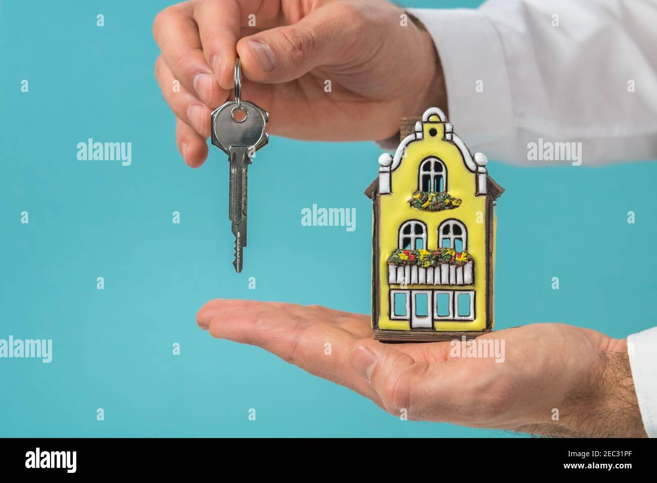 Nice house model and key in hand, turquoise background for copy space - real estate concept Stock Photo