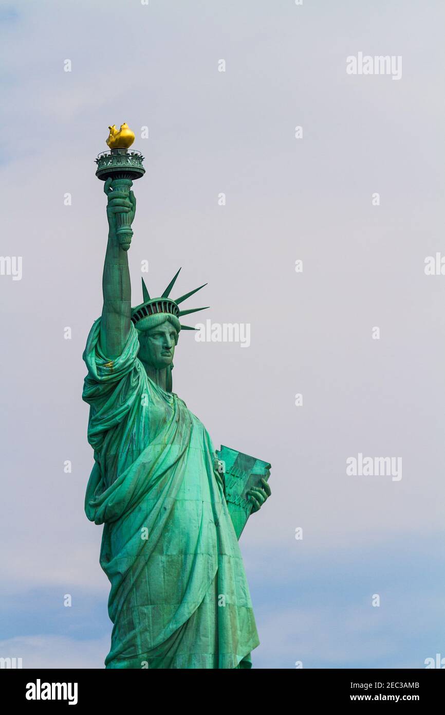 A close up vertical image of the Statue of Liberty on cloudy background Stock Photo