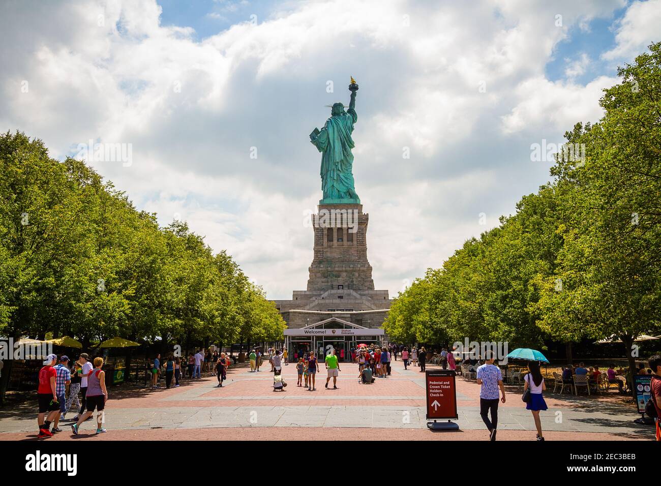 Tourists walking around the entrance of the Statue of Liberty behind