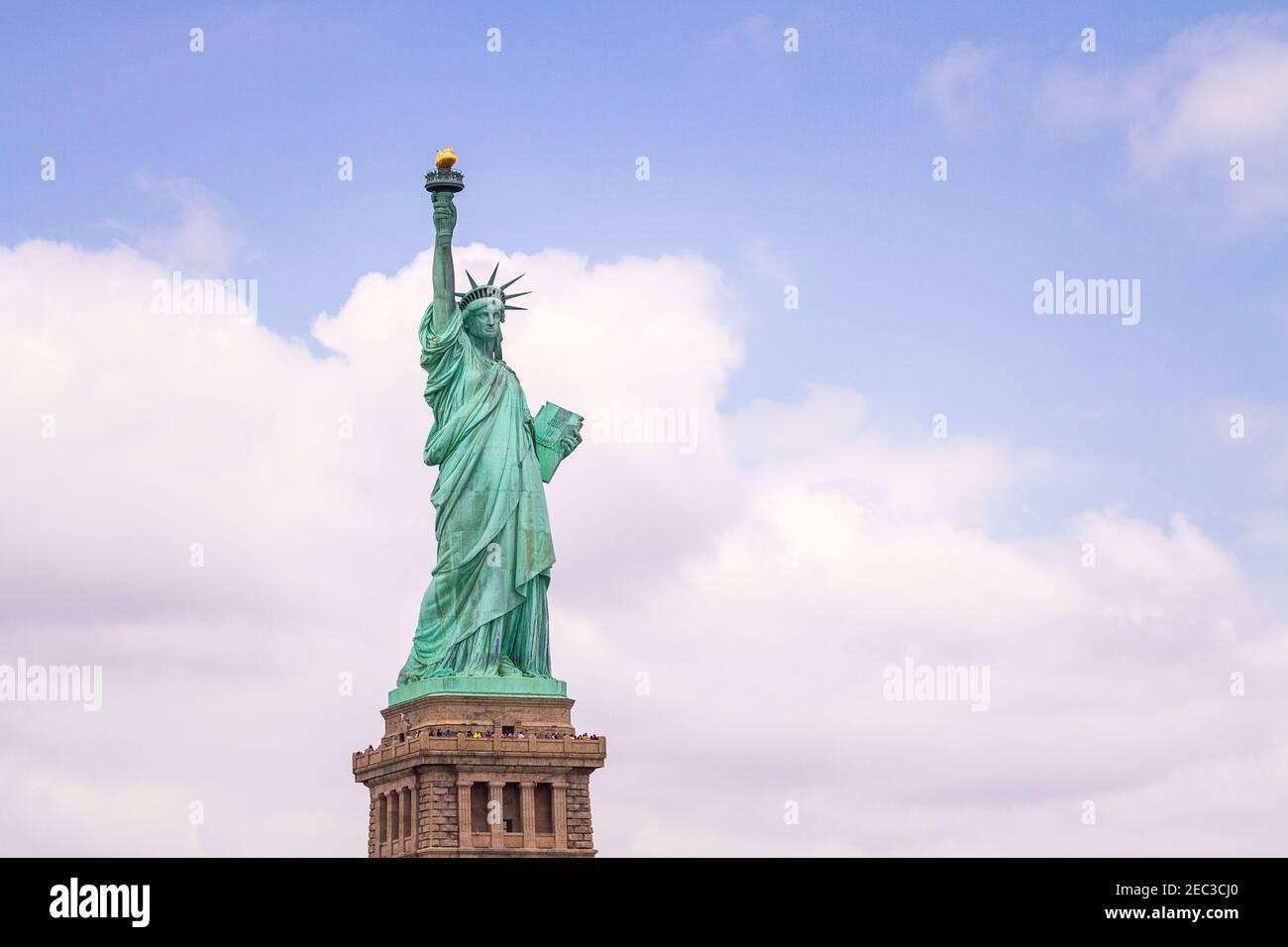 View of the Statue of Liberty in New York from the left front side with the blue cloudy sky in the background Stock Photo