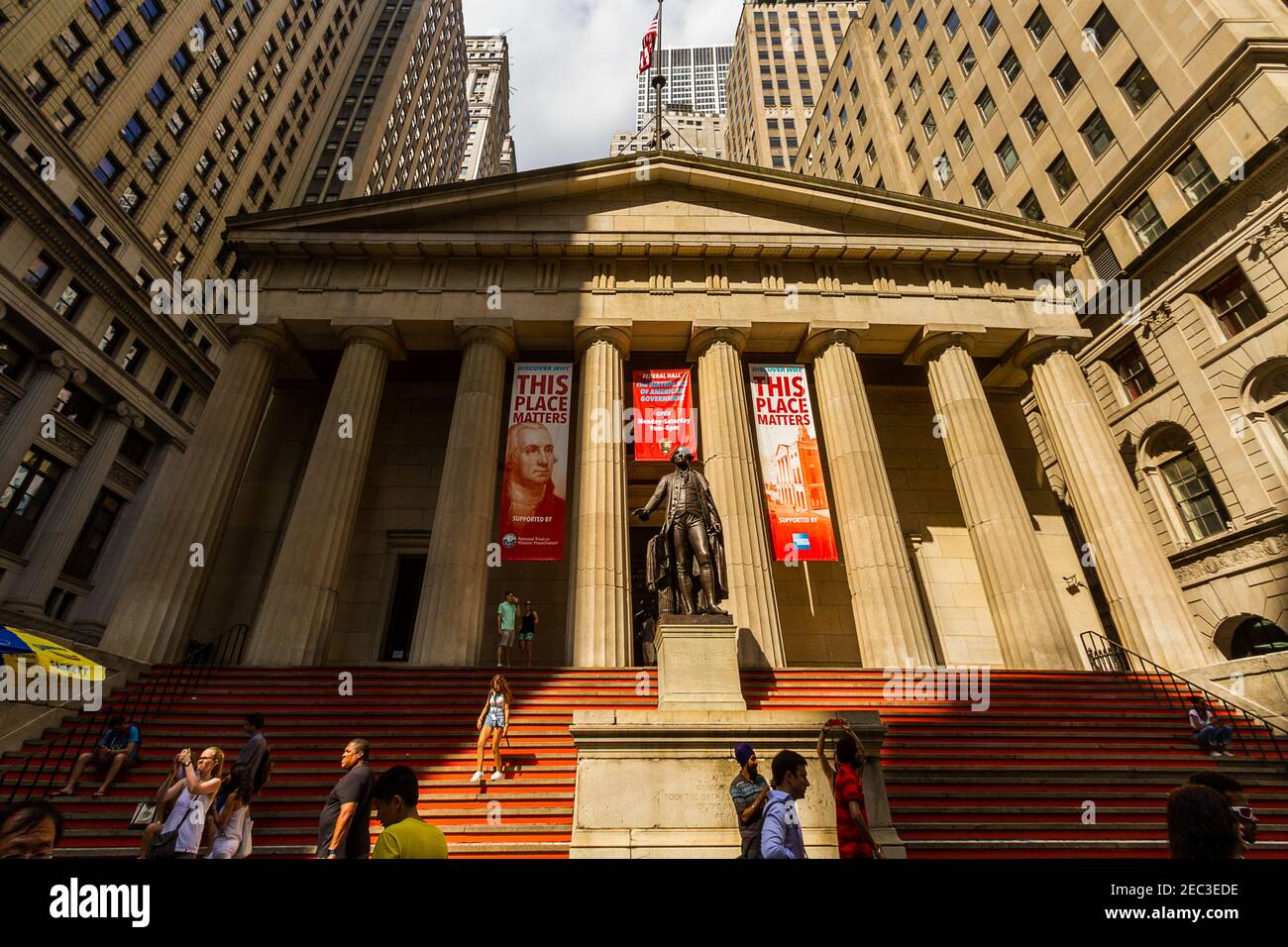 Front view of the Federal Hall at 26 Wall Street in the Financial District with the statue of George Washington and tourists walking and taking photos Stock Photo