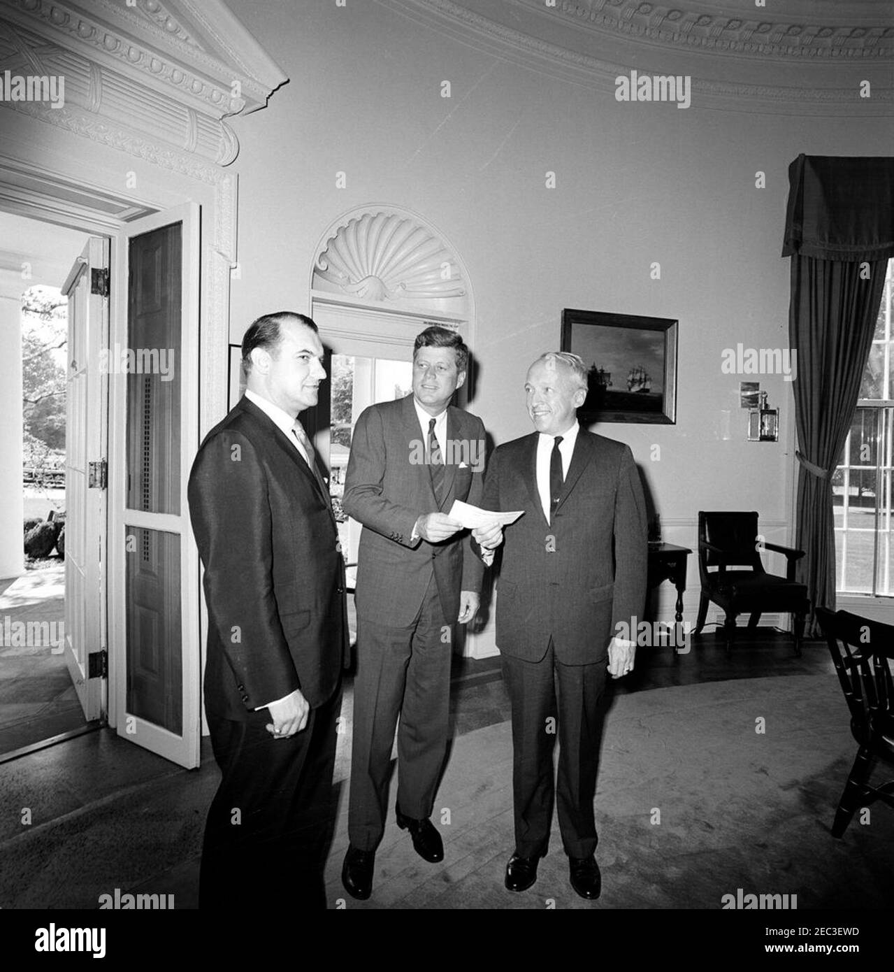 Visit of the Postmaster General J. Edward Day u0026 Chairman, United Givers Fund (UGF), 11:00AM. President John F. Kennedy stands with Postmaster General, J. Edward Day (right), and Chairman of the United Givers Fund of the National Capital Area, William Calomiris (left). Oval Office, White House, Washington, D.C. Stock Photo