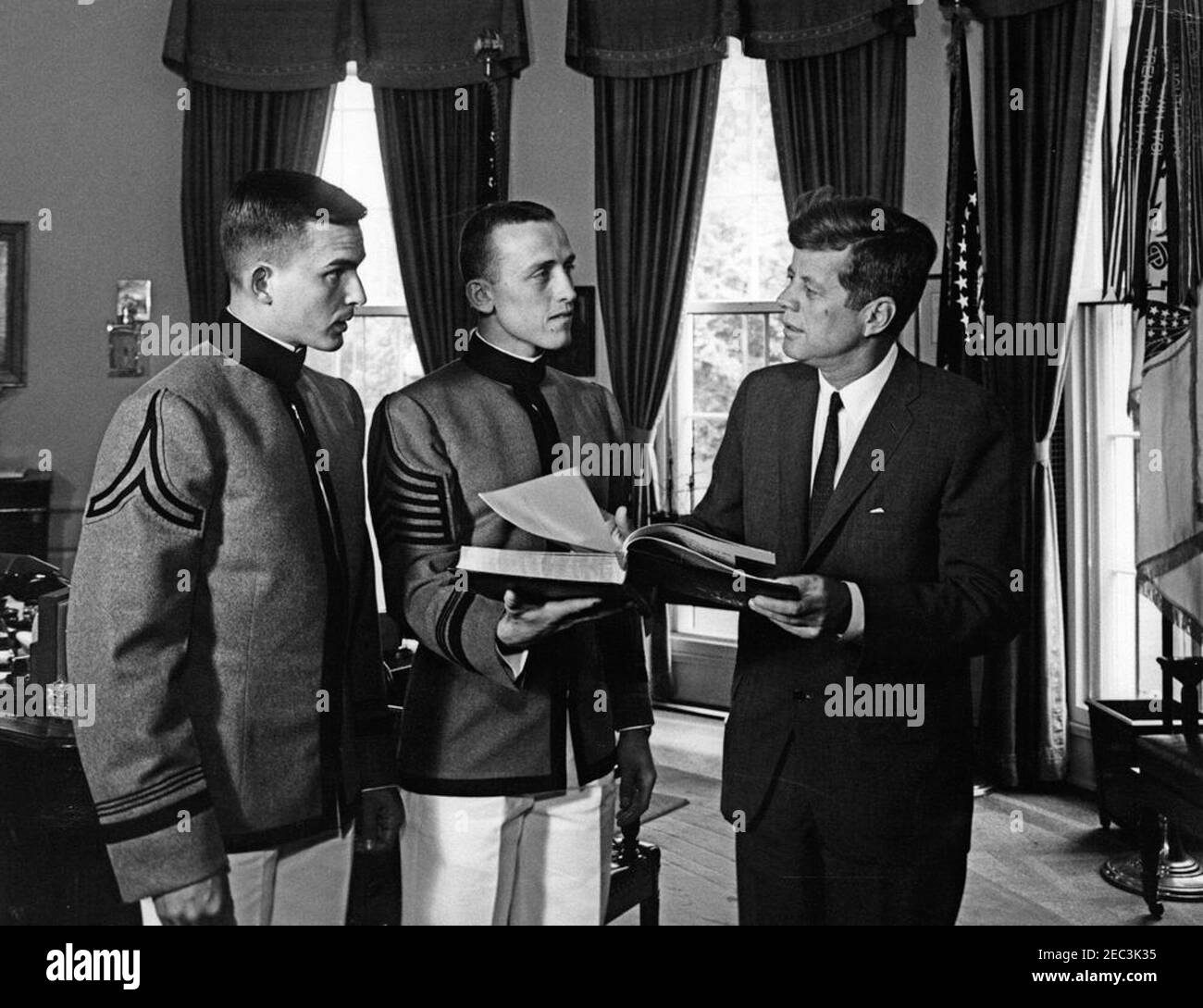 Presentation of the US Military Academy at West Point Yearbook, Howitzer, to President Kennedy, 12:12PM. United States Military Academy cadets of West Point present President John F. Kennedy with a copy of the 1963 u0022Howitzeru0022 yearbook. (L-R) Cadet David W. Knowlton, editor of the yearbook; Cadet First Captain Lyndol L. Cook, class president; and President Kennedy. Oval Office, White House, Washington, D.C. Stock Photo