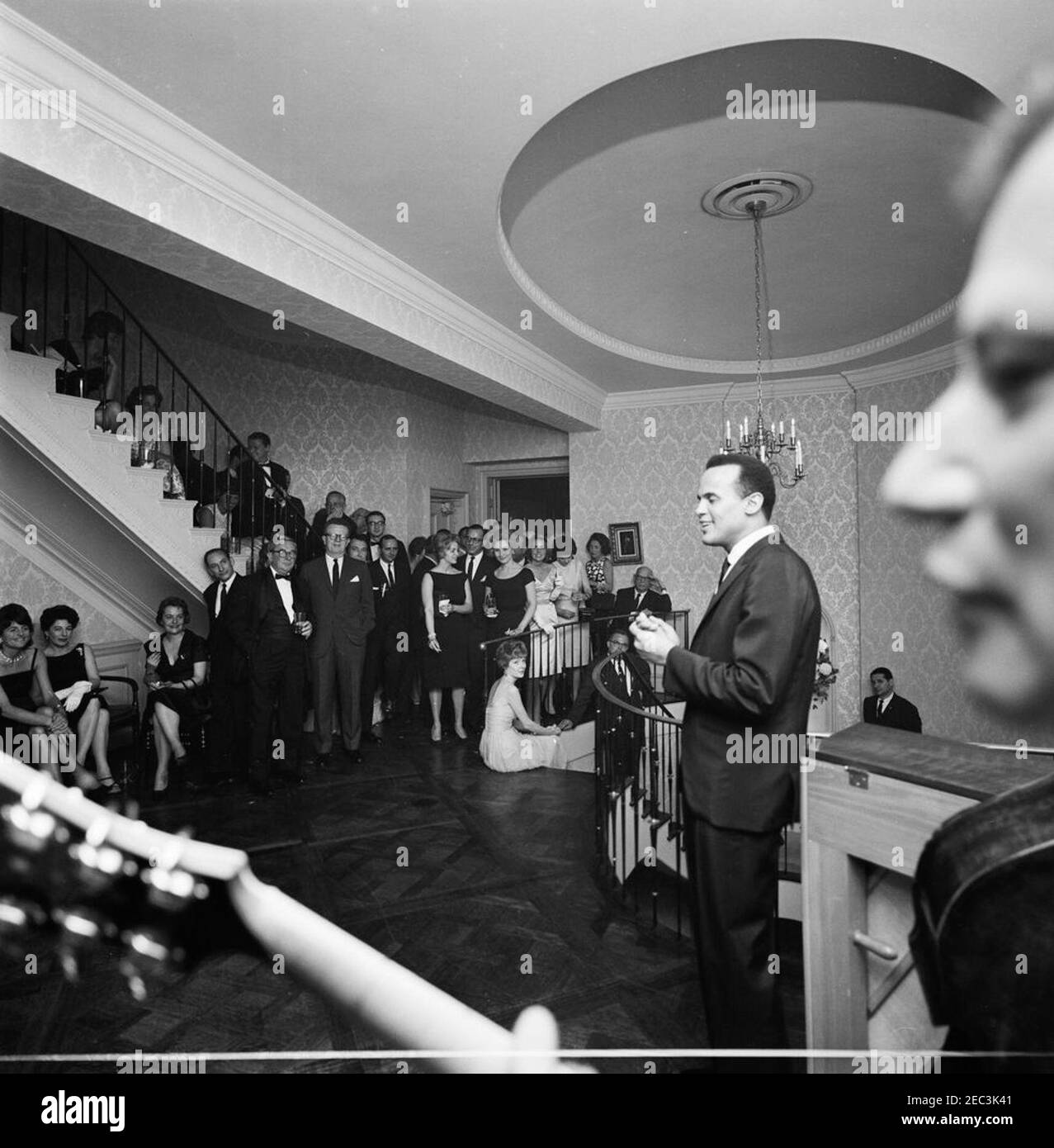 Trip to New York City: Reception, Arthur Krim Residence. Singer, Harry Belafonte (far right), performs during an evening reception at the residence of Arthur B. Krim and Dr. Mathilde Krim in New York City, New York. Also pictured: Patricia Kennedy Lawford; Jean Kennedy Smith; comedian, Mike Nichols; Special Assistant to the President for Congressional Relations, Larry Ou0027Brien; White House Secret Service agent, Floyd Boring. Stock Photo