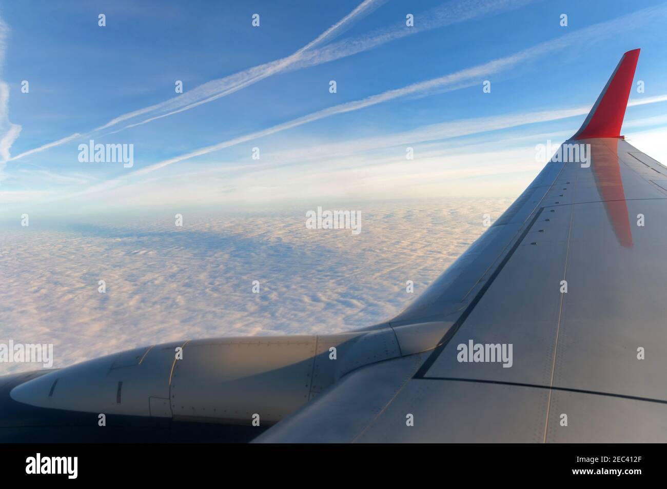 Wing of an airplane flying above the clouds. People looks at the sky from the window of the plane, using airtransport to travel. Endless clouds Stock Photo