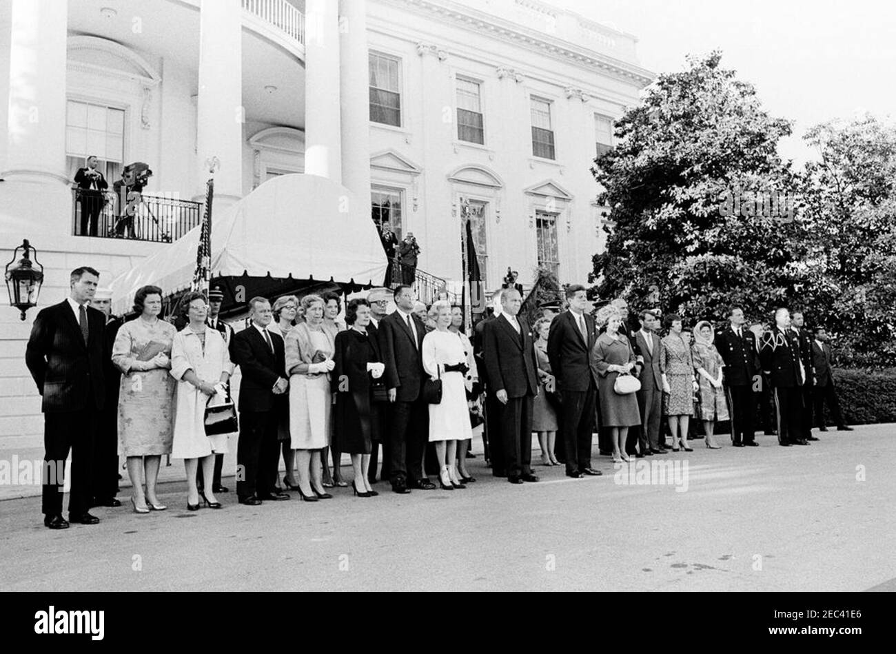President Kennedy greets recipients of the Congressional Medal of Honor, Annual Military Reception, 6:03PM. President John F. Kennedy and others attend a military reception in honor of recipients of the Congressional Medal of Honor. Left to right: several unidentified persons; Margaret McNamara (wearing black coat), wife of Robert S. McNamara, Secretary of Defense; Secretary of the Navy, Fred Korth (in back); Secretary McNamara; unidentified man (in back); Madelin T. Gilpatric, wife of Roswell L. Gilpatric, Deputy Secretary of Defense; Phyllis Chess Ellsworth, wife of C. Douglas Dillon, Secret Stock Photo