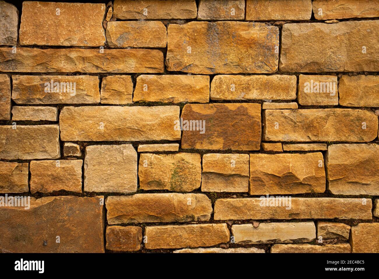 A yellow orange sandstone wall with square rectangle shaped bricks Stock Photo