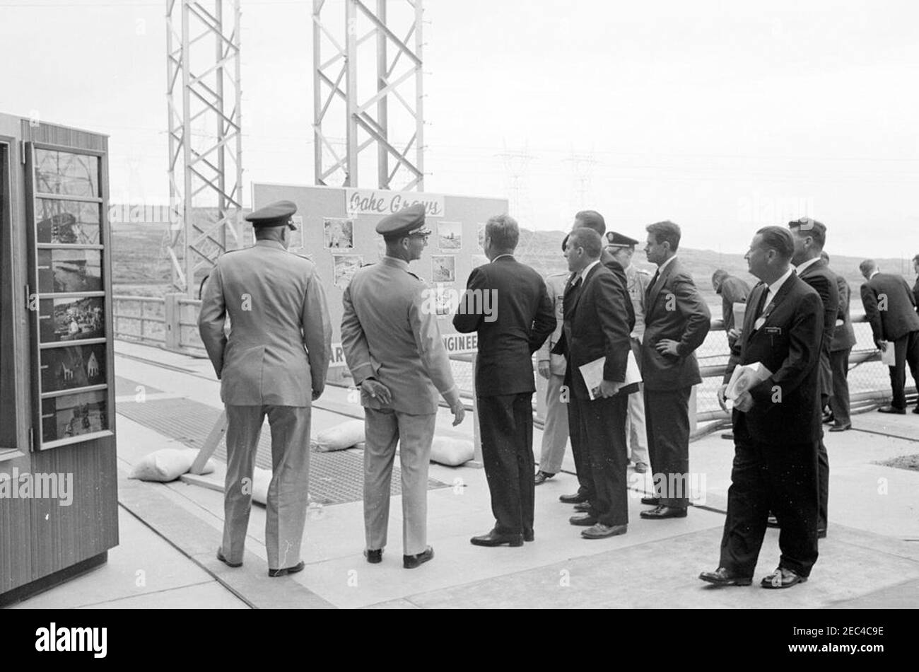 Trip to Western States: Pierre, South Dakota (Oahe Dam), 10:25AM. President John F. Kennedy (center, with back to camera) views U.S. Army Corps of Engineersu0027 displays during the dedication ceremony of the Oahe Dam and Reservoir, on the banks of the Missouri River, near Pierre, South Dakota. Also pictured: Omaha District Engineer, Colonel Harry G. Woodbury, Jr.; Secretary of the Interior, Stewart L. Udall; Governor of South Dakota, Archie M. Gubbrud (mostly hidden); Secretary of the Army, Cyrus R. Vance; Oahe Area Engineer, John W. Sibert, Jr. [White spots on image are original to the nega Stock Photo