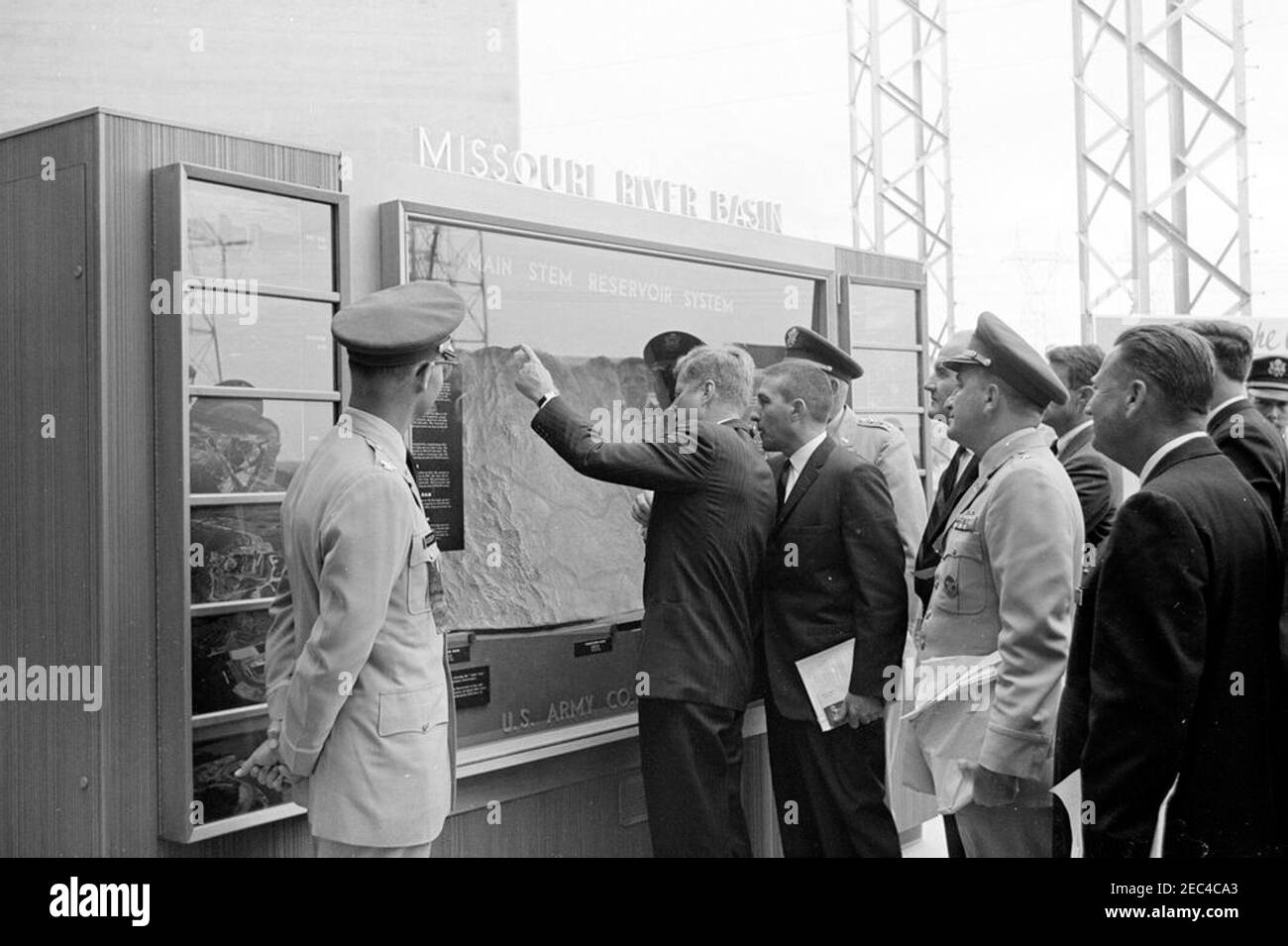 Trip to Western States: Pierre, South Dakota (Oahe Dam), 10:25AM. President John F. Kennedy views U.S. Army Corps of Engineersu0027 displays during the dedication ceremony of the Oahe Dam and Reservoir, on the banks of the Missouri River, near Pierre, South Dakota. Looking on (L-R): Omaha District Engineer, Colonel Harry G. Woodbury, Jr.; Secretary of the Interior, Stewart L. Udall; Missouri River Division Engineer, Brigadier General Robert F. Seedlock; U.S. Senatorial candidate from South Dakota, George McGovern (partially hidden); Secretary of the Army, Cyrus R. Vance (face obscured); Oahe Stock Photo