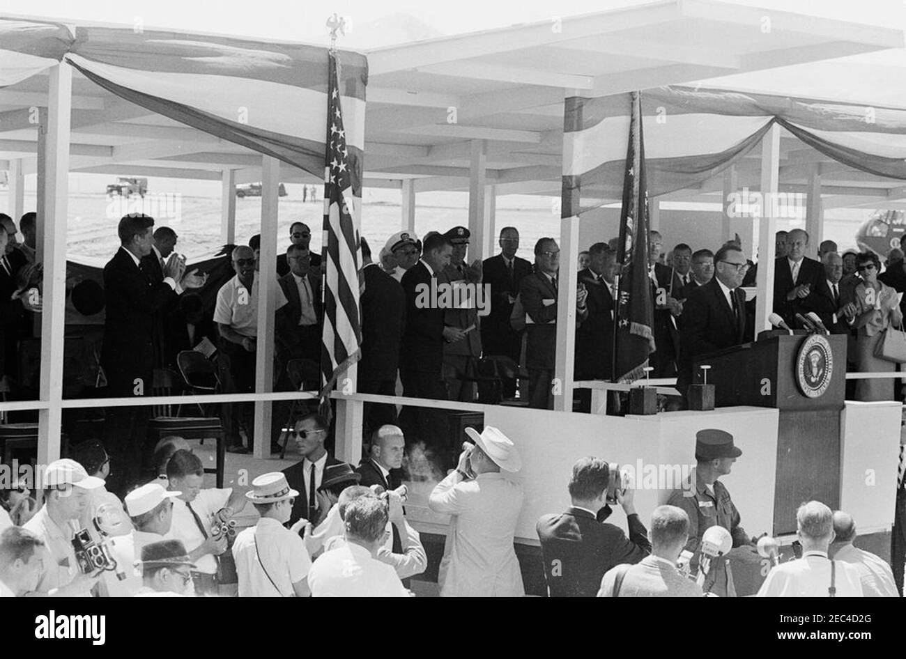 Trip to Western States: Los Banos, California (San Luis Dam), 11:40AM. President John F. Kennedy (left) and others applaud as Governor of California, Edmund G. u201cPatu201d Brown (at lectern), delivers remarks at the groundbreaking ceremony for the San Luis Dam in Los Banos, California. Others standing on speakersu0027 platform include: Secretary of the Interior, Stewart L. Udall; Senators Thomas H. Kuchel and Clair Engle (both of California); Under Secretary of the Interior, James K. Carr. White House Secret Service agent, Bob Lilley, and United Press International (UPI) photographer, Jam Stock Photo