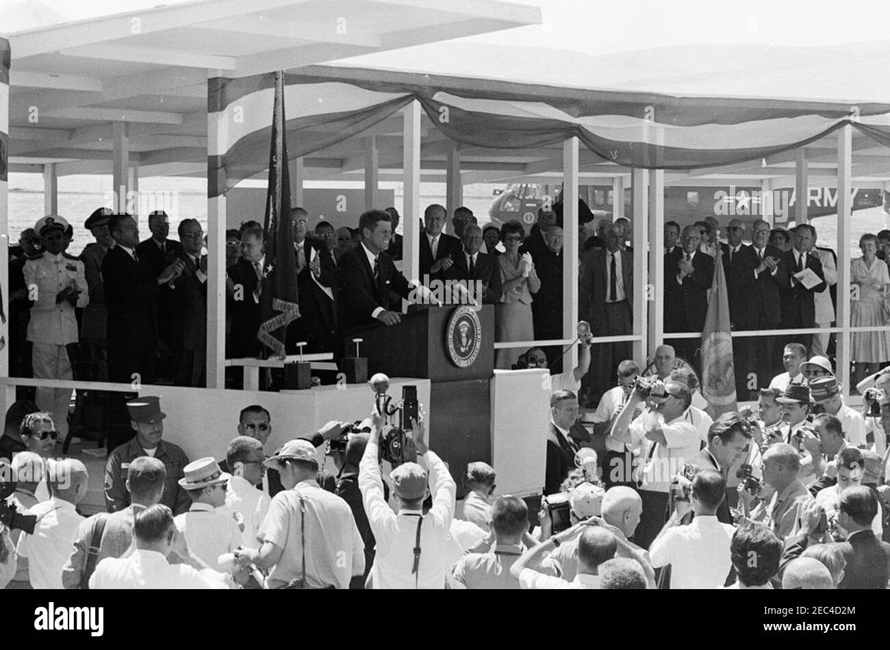 Trip to Western States: Los Banos, California (San Luis Dam), 11:40AM. President John F. Kennedy (at lectern) delivers remarks at the groundbreaking ceremony for the San Luis Dam in Los Banos, California. Those standing on speakersu0027 platform include: Secretary of the Interior, Stewart L. Udall; Senators Thomas H. Kuchel and Clair Engle (both of California). White House Secret Service agents, Bob Lilley and Win Lawson, stand in front of platform; members of the press observe. Stock Photo