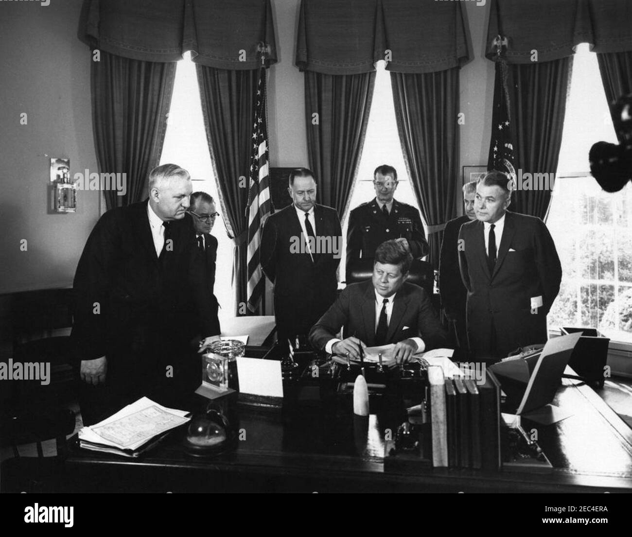 President Kennedy signs emergency flood relief measures for Kentucky counties, 11:30AM. President John F. Kennedy (seated at desk) signs emergency flood relief measures for Kentucky counties in the Oval Office of the White House, Washington, D.C. Standing (L-R): Congressman Carl D. Perkins (Kentucky); Mayor Paul Judd of Frankfort, Kentucky; Congressman John C. Watts (Kentucky); Adjutant General of Kentucky, A. Y. Lloyd; Administrative Assistant to Congressman Watts, Paul Kelly; Governor of Kentucky, Bert T. Combs. Stock Photo