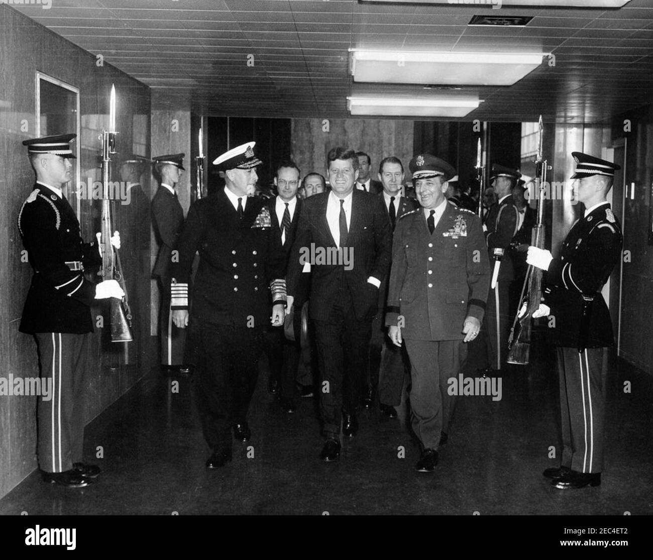 Address to the Chiefs of Staff of NATO (North Atlantic Treaty Organization) Nations, 10:03AM. President John F. Kennedy walks through a hallway of the State Department; the President delivered an address to the Chiefs of Staff of NATO (North Atlantic Treaty Organization) Nations. L-R: Two unidentified honor guard members; Chief of the Defense Staff of the British Armed Forces, Lord Louis Mountbatten, First Earl Mountbatten of Burma; Special Assistant to the President on Foreign Affairs, McGeorge Bundy; unidentified man (in back); President Kennedy; Kennedy family friend, Charles Spalding (face Stock Photo