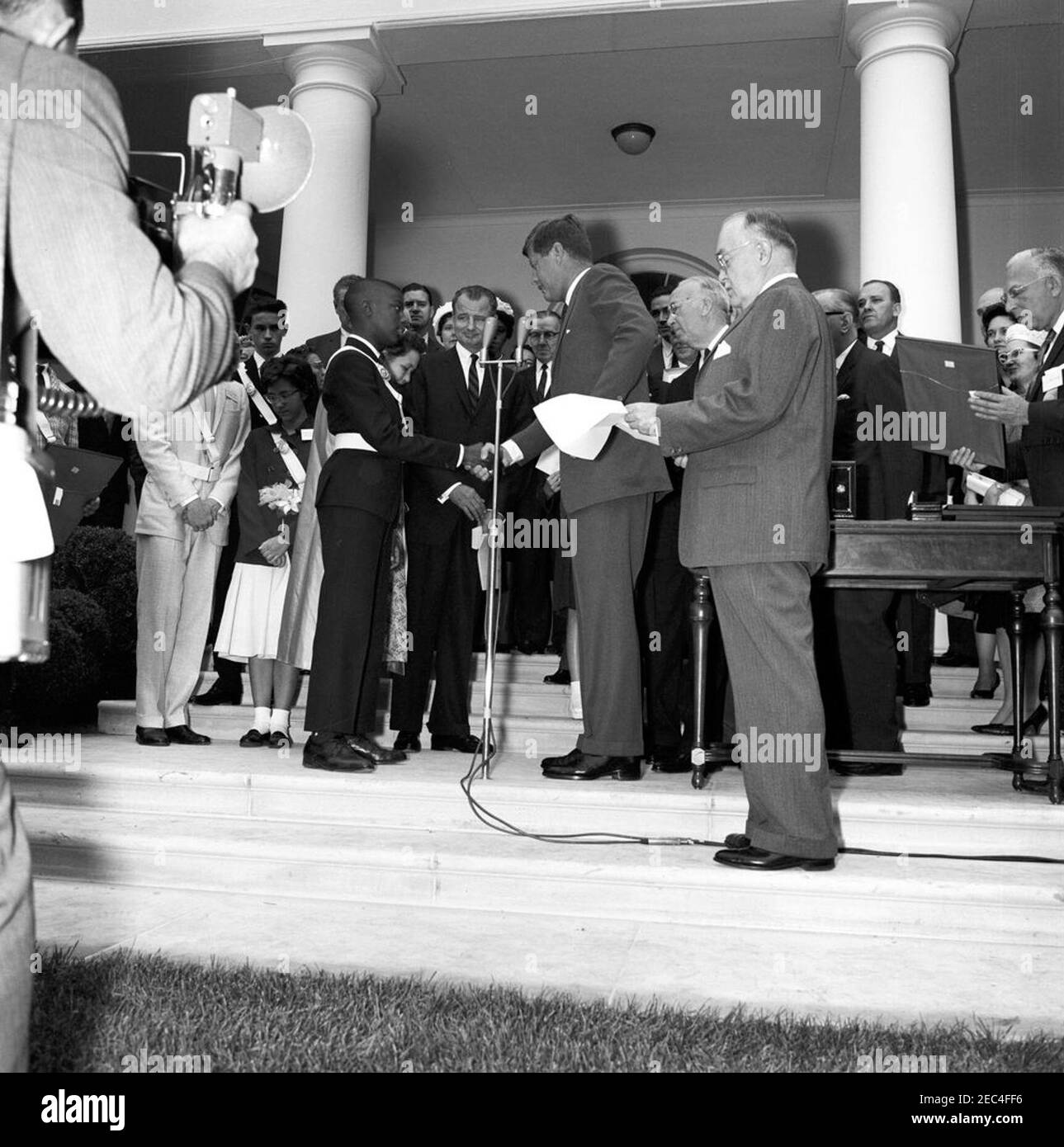 Presentation of the American Automobile Association (AAA) Lifesaving Awards in the Rose Garden, 9:50AM. President John F. Kennedy shakes hands with Wayne Brown (of New York, New York) upon presenting him with the American Automobile Association (AAA) Lifesaving Award; four other members of the organizationu2019s School Safety Patrol also received the award. Those pictured include: award recipients, Wesley Haines (of Dayton, Ohio), John Puhak (of Hazelton, Pennsylvania), and Patricia Miller (of Hereford, Pennsylvania); Ambassador of Norway, Paul Koht; Senator George A. Smathers (Florida); Repr Stock Photo